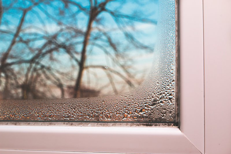 Il telaio di una finestra con condensa sui bordi e sugli angoli.
