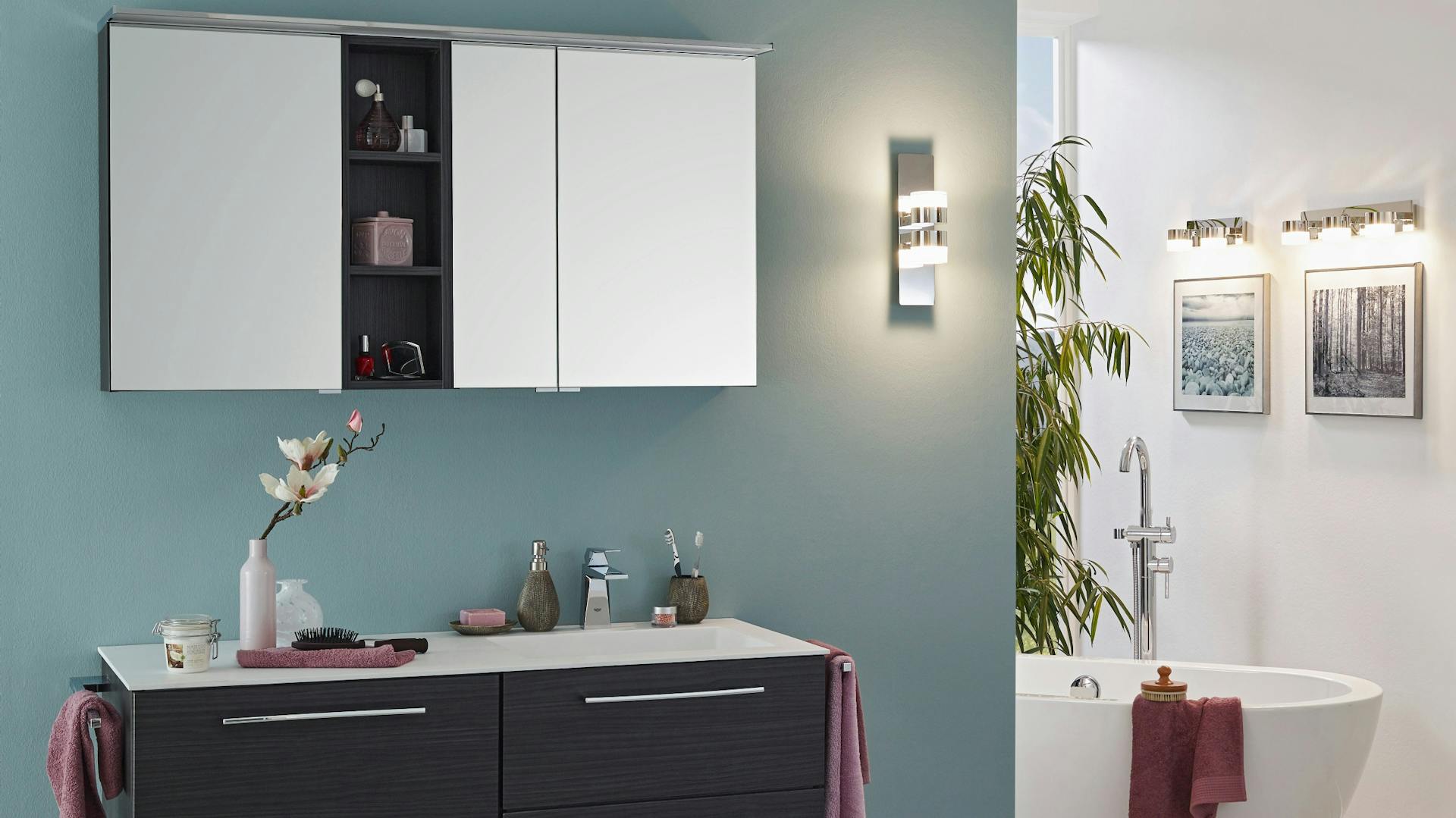 Bad mit Badewanne in Ecke Waschbecken Spiegel und Wandbeleuchtung neben 'Spiegel und über Bildern