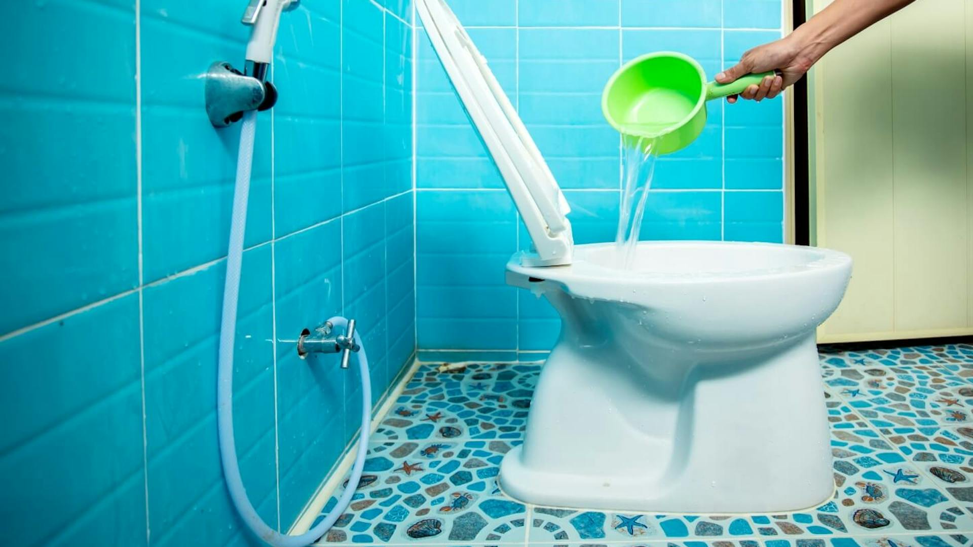 Person kippt Wasser aus einem grünen Behältnis in die Toilette.