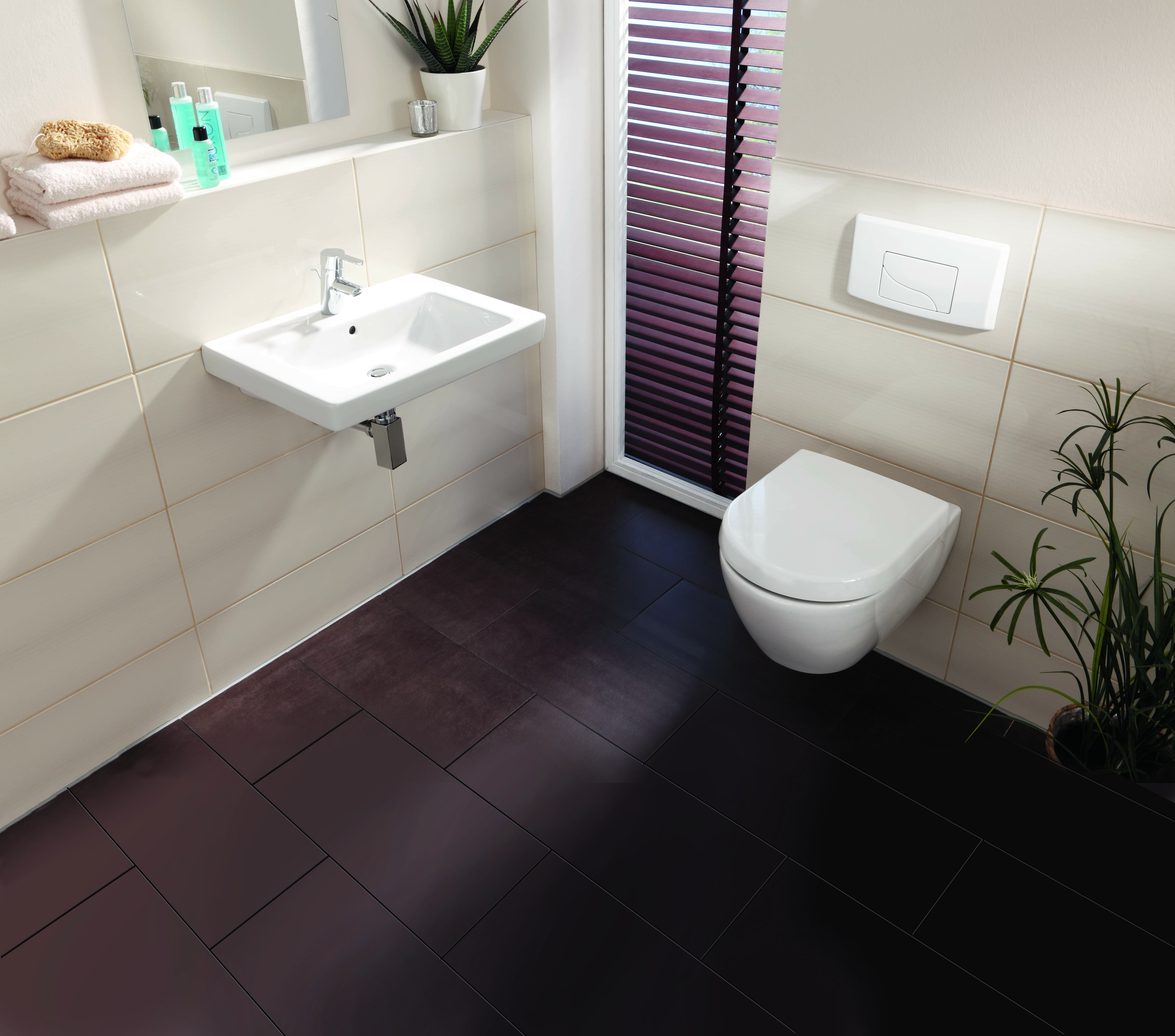 Modernes Badezimmer mit Toilette und weißem Toilettendeckel.