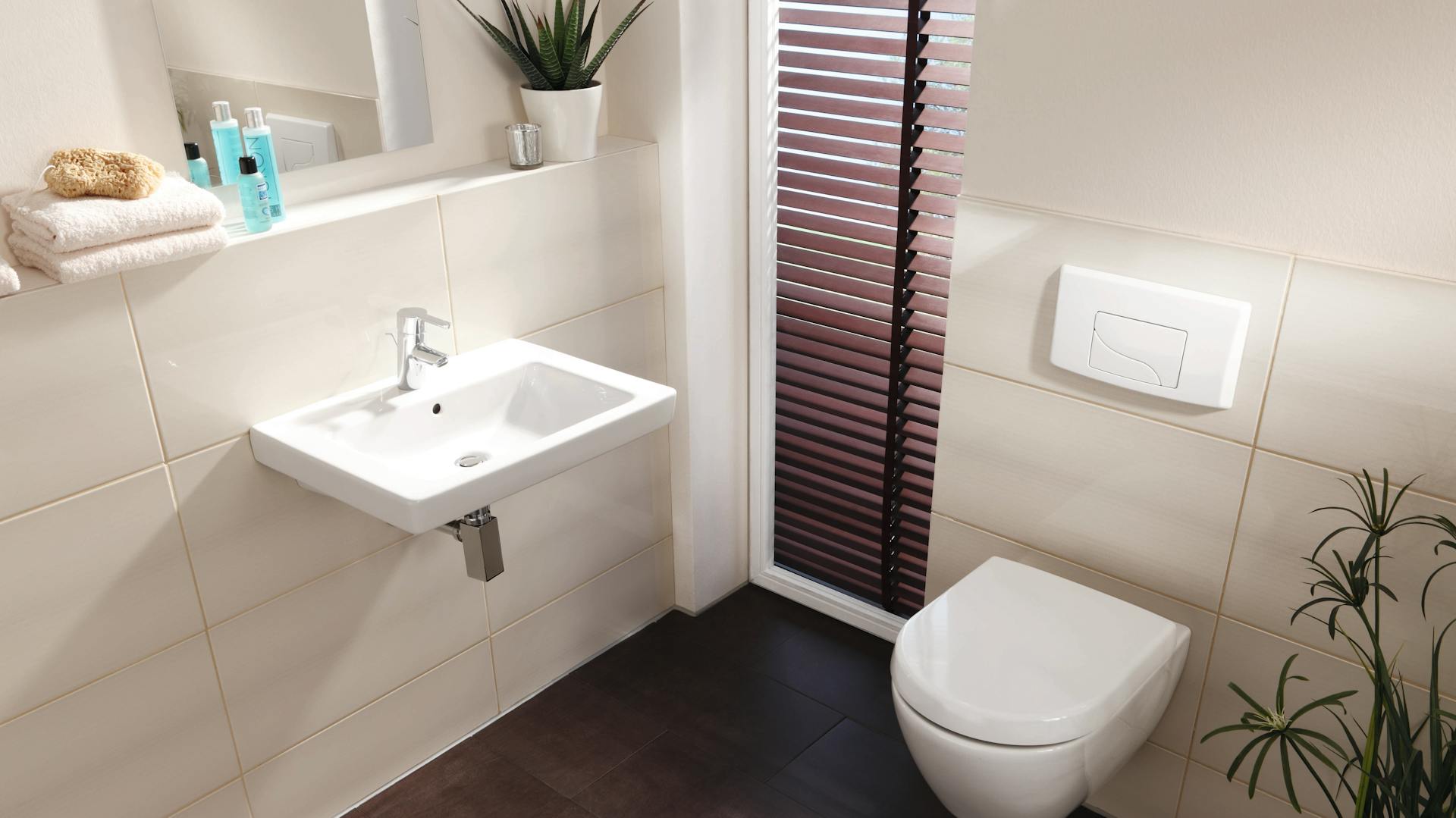 Wand-WC in modernem Bad mit dunklen Fliesen und Handtuchheizkörper