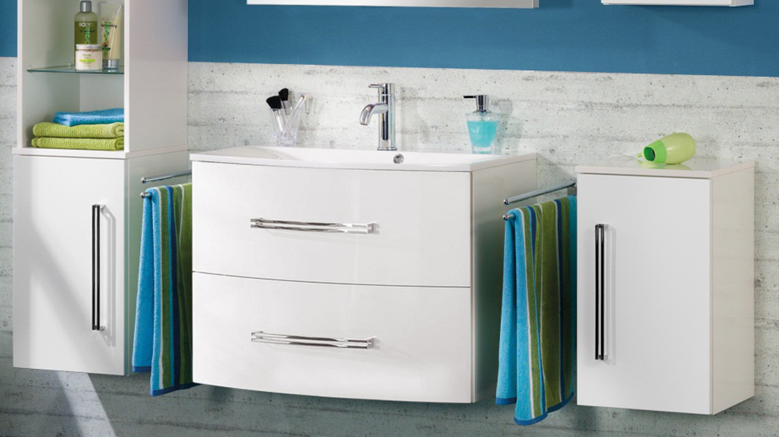 Eckiges, weißes Einbauwaschbecken mit weißem Unterbau mit Schubladen zwischen Hängeschränken.