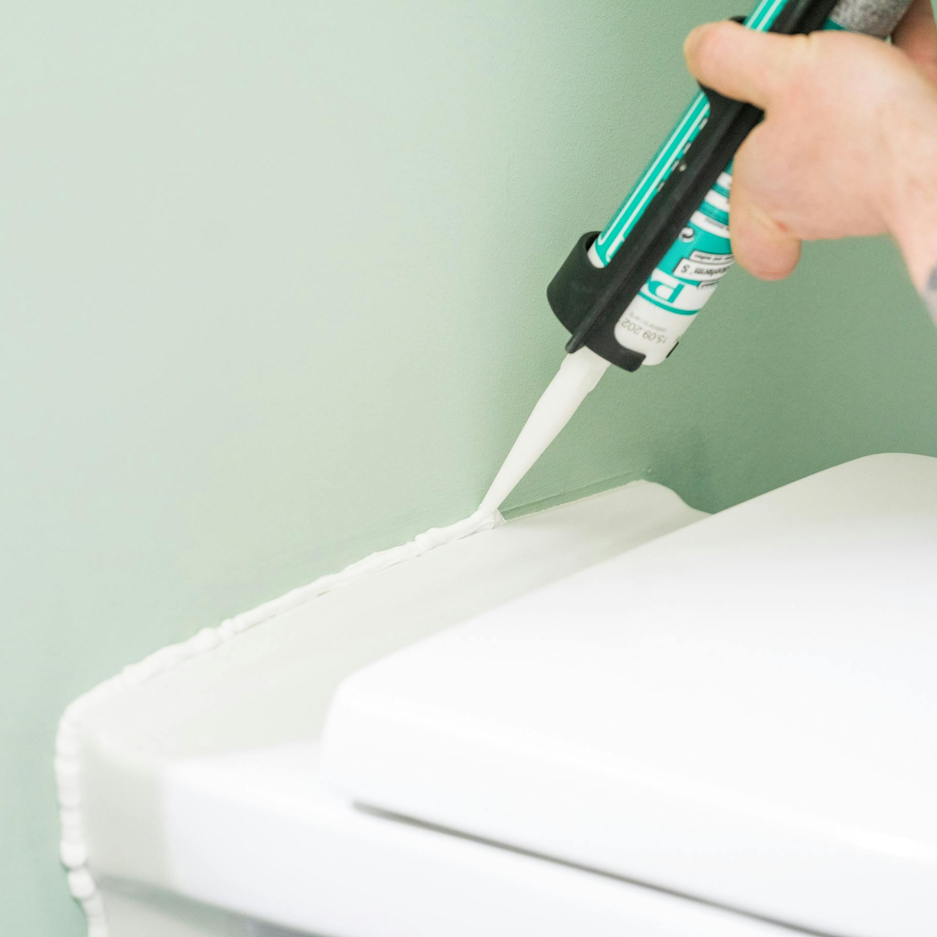 Heimwerker dichtet Wand-WC ab.