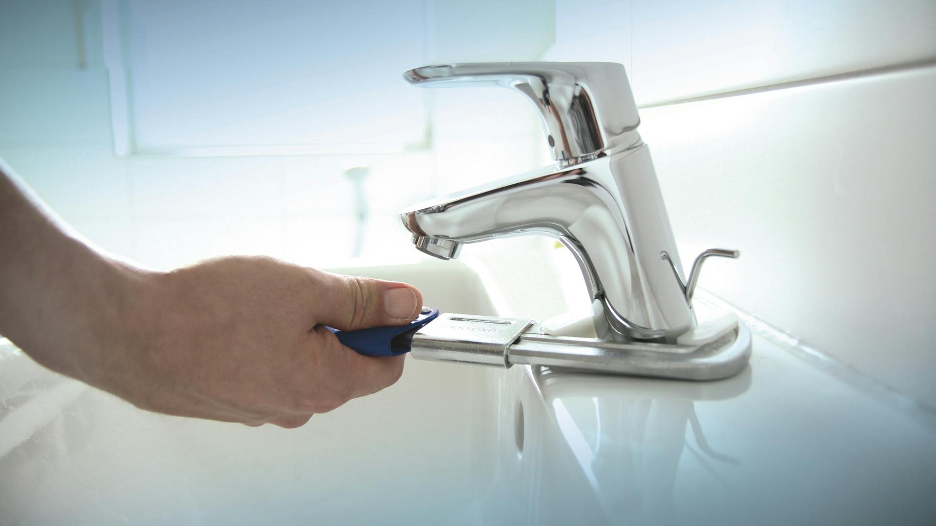 Heimwerker montiert Armatur am Waschbecken mit der Zange.