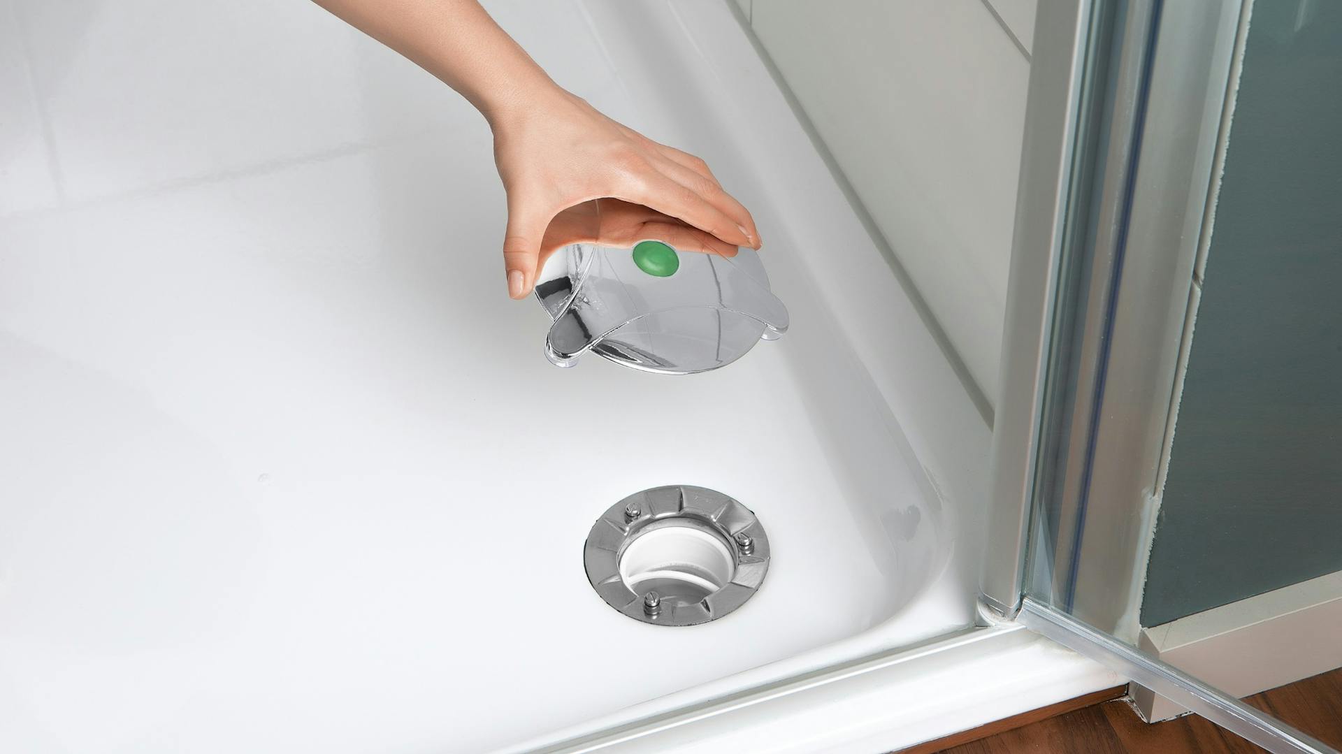 Hand setzt Abflussstopfen auf montiertem Wasserabfluss von Dusche