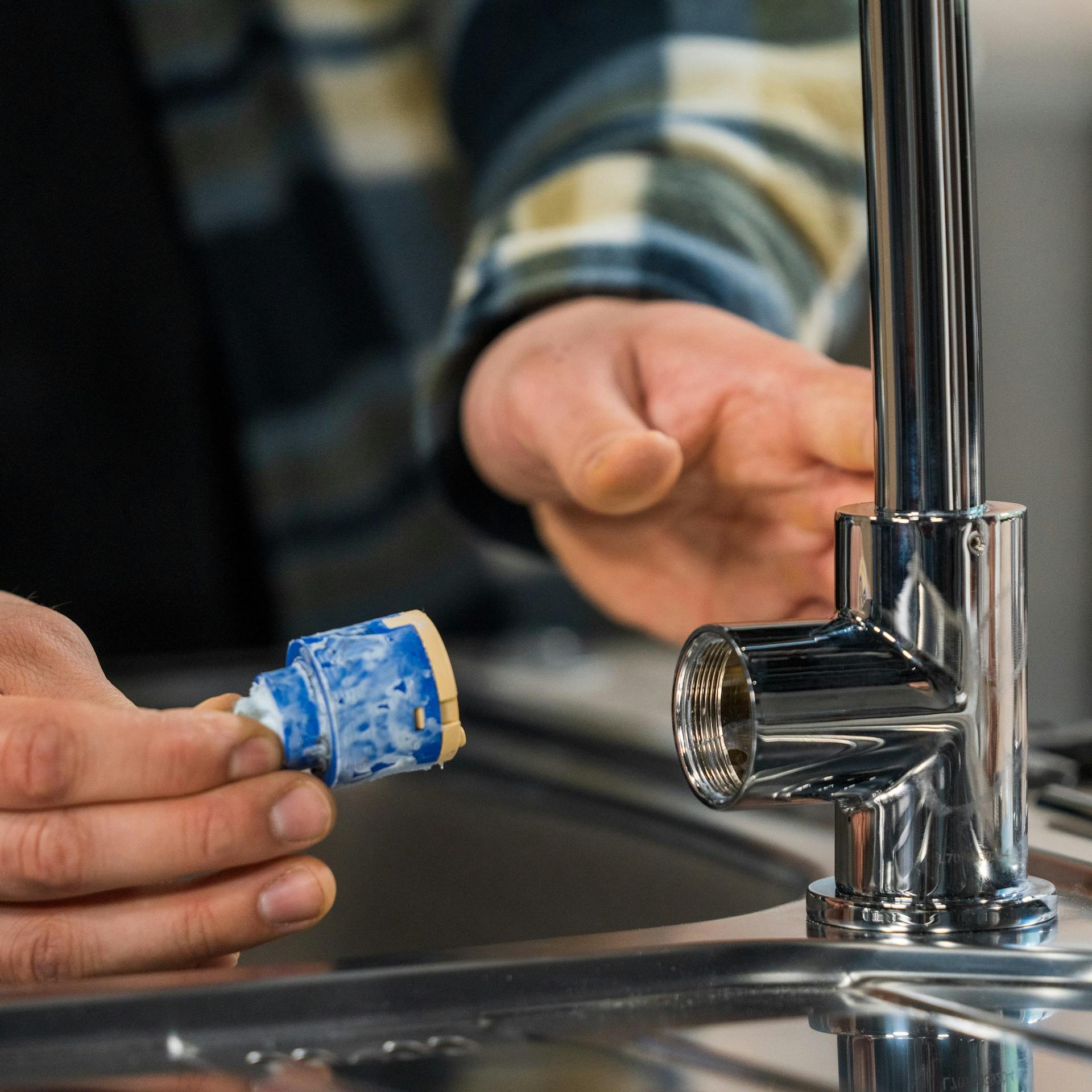 Heimwerker tauscht eine Kartusche am Wasserhahn aus.