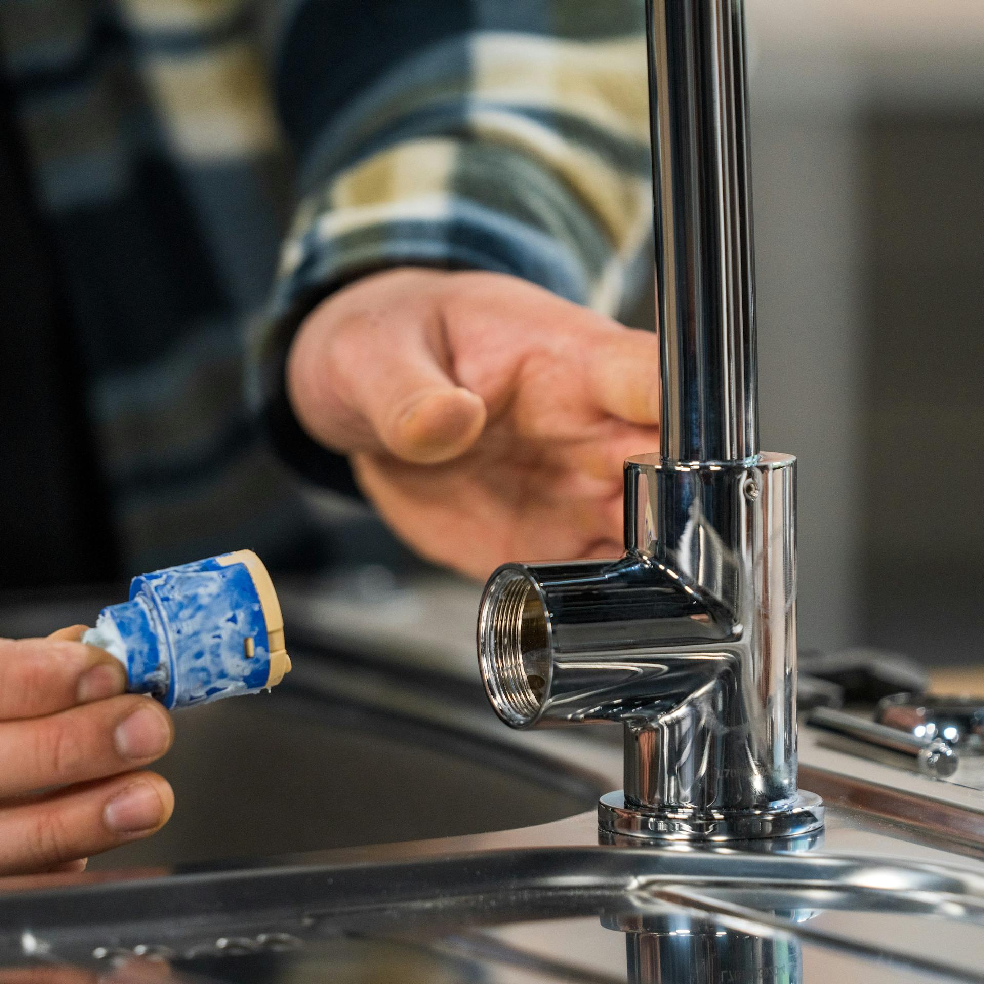 Appassionato del fai da te sostituisce una cartuccia nel rubinetto.