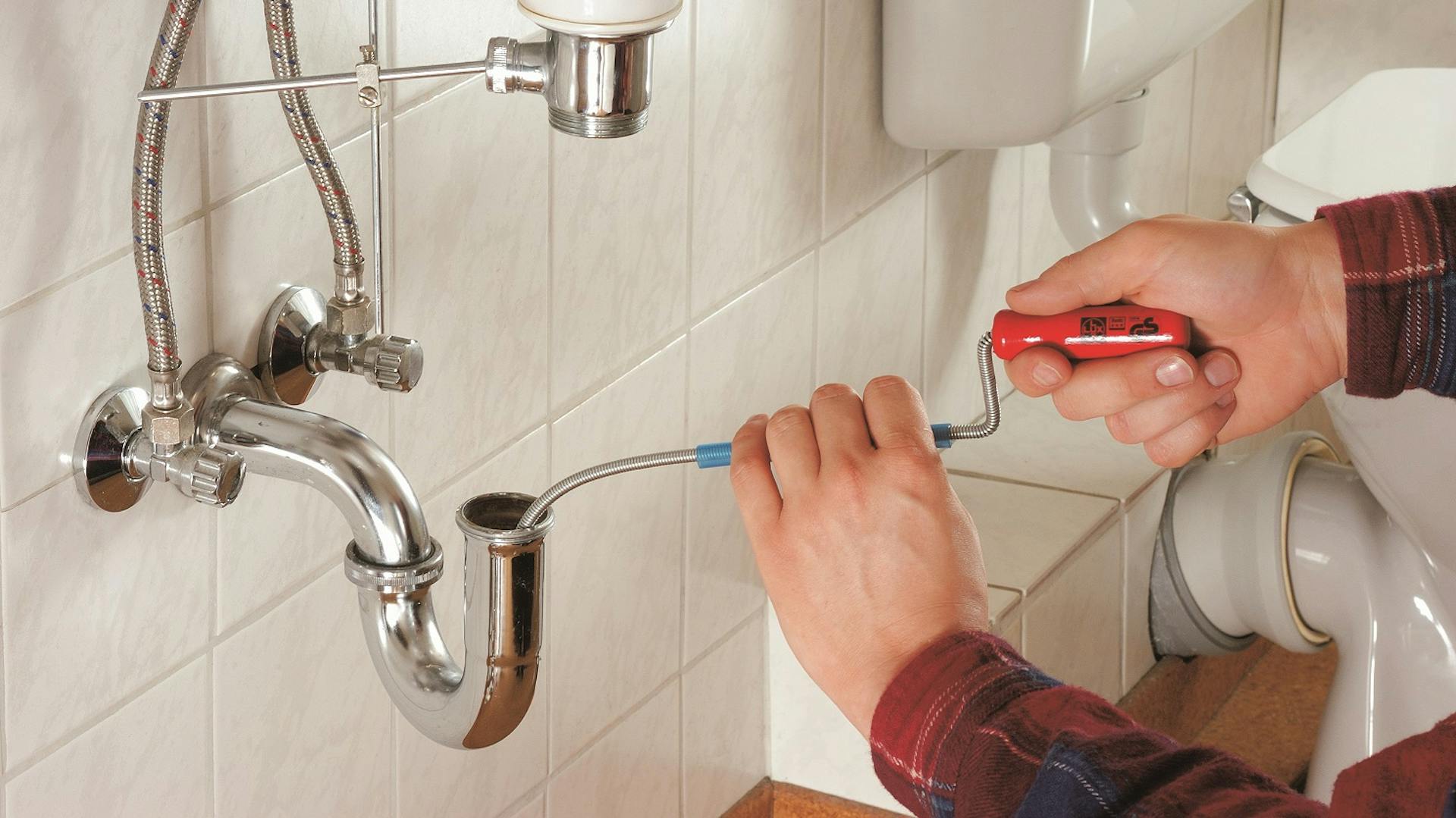 Vízelvezető cső csatlakozásának ellenőrzése egy mosdó alatt.