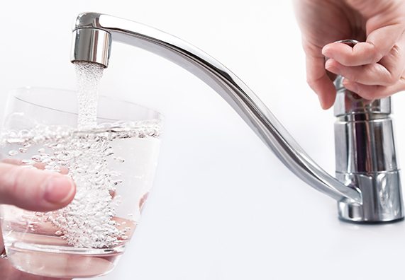 Aus einem Wasserhahn wird Trinkwasser in ein Glas gefüllt.