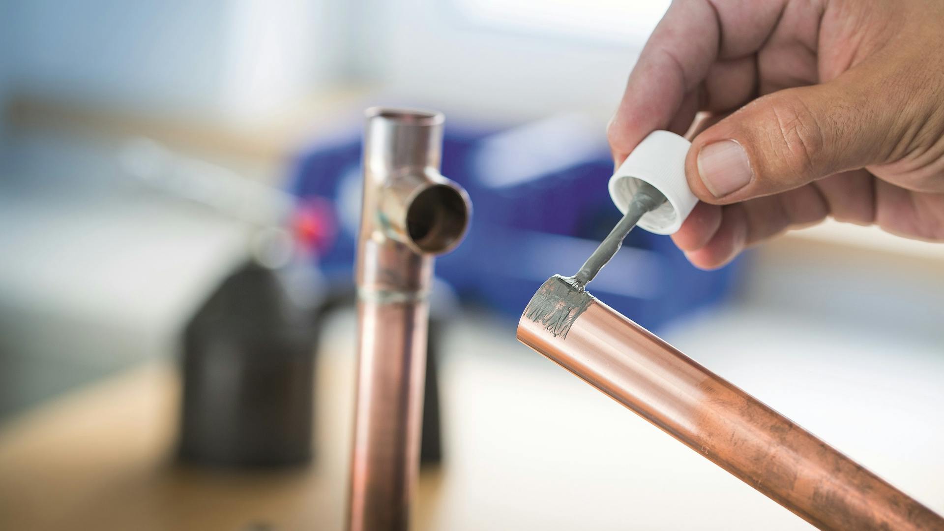 Jemand bereitet eine Wasserleitung aus Kupfer für den Anschluss vor.