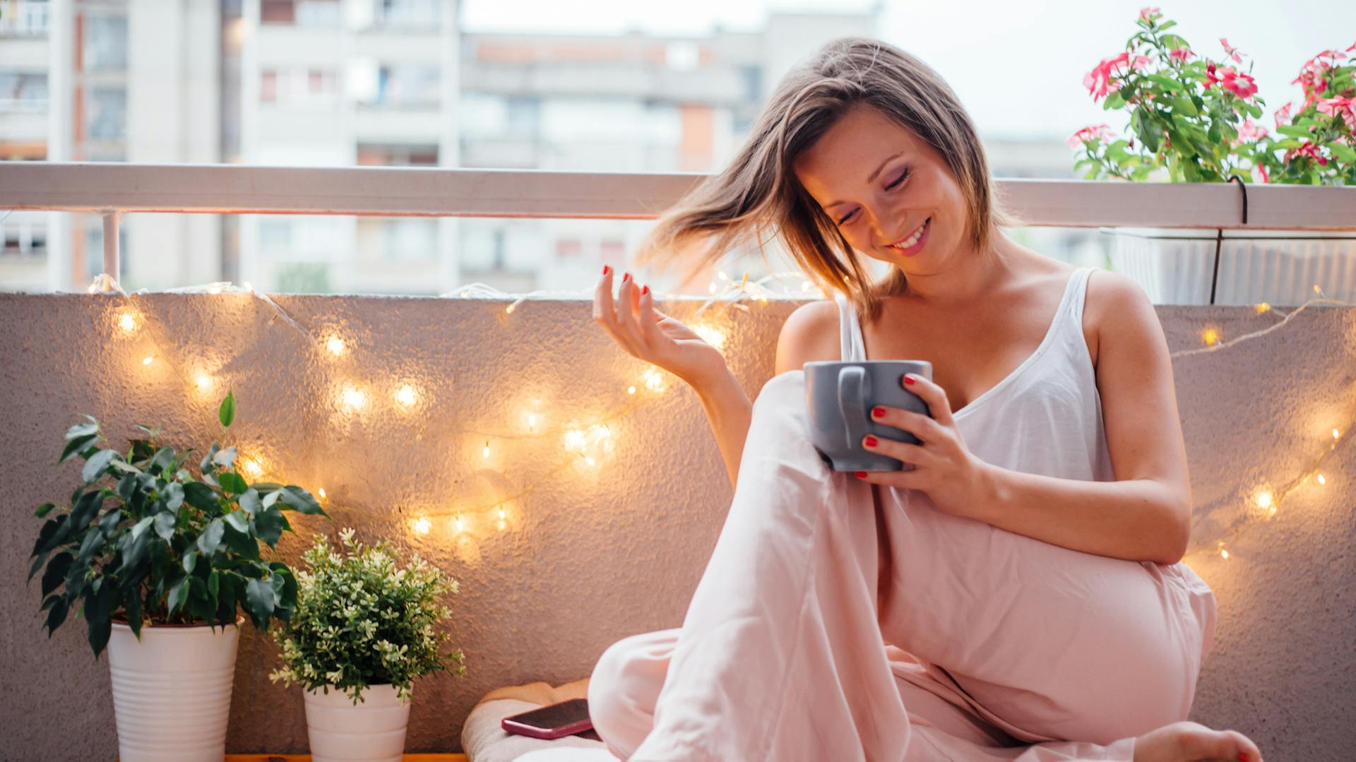 Nő egy hangulatos, fényfüzéres erkélyen.