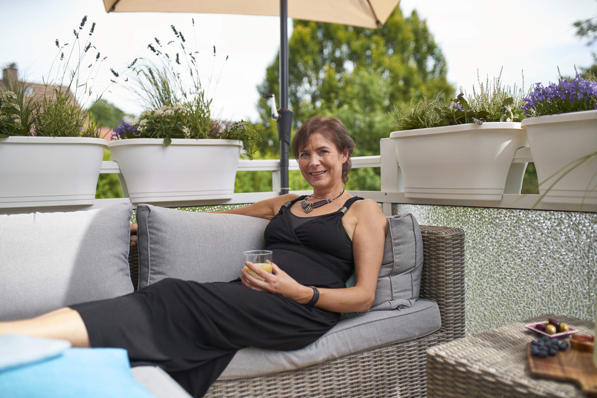 Frau mit Getränk sitzt auch Gartenlounge