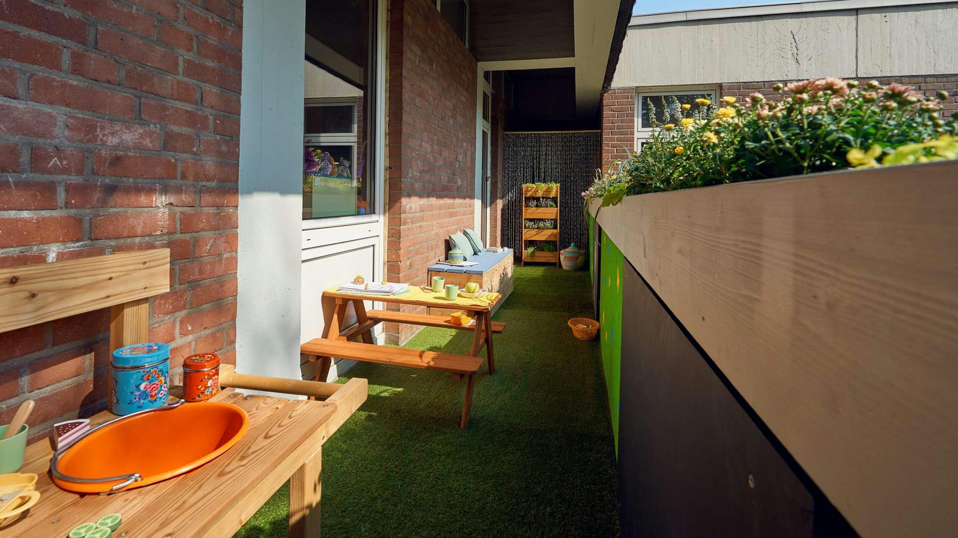 Kleine Matschküche auf schmalem Balkon neben Sitzgruppe