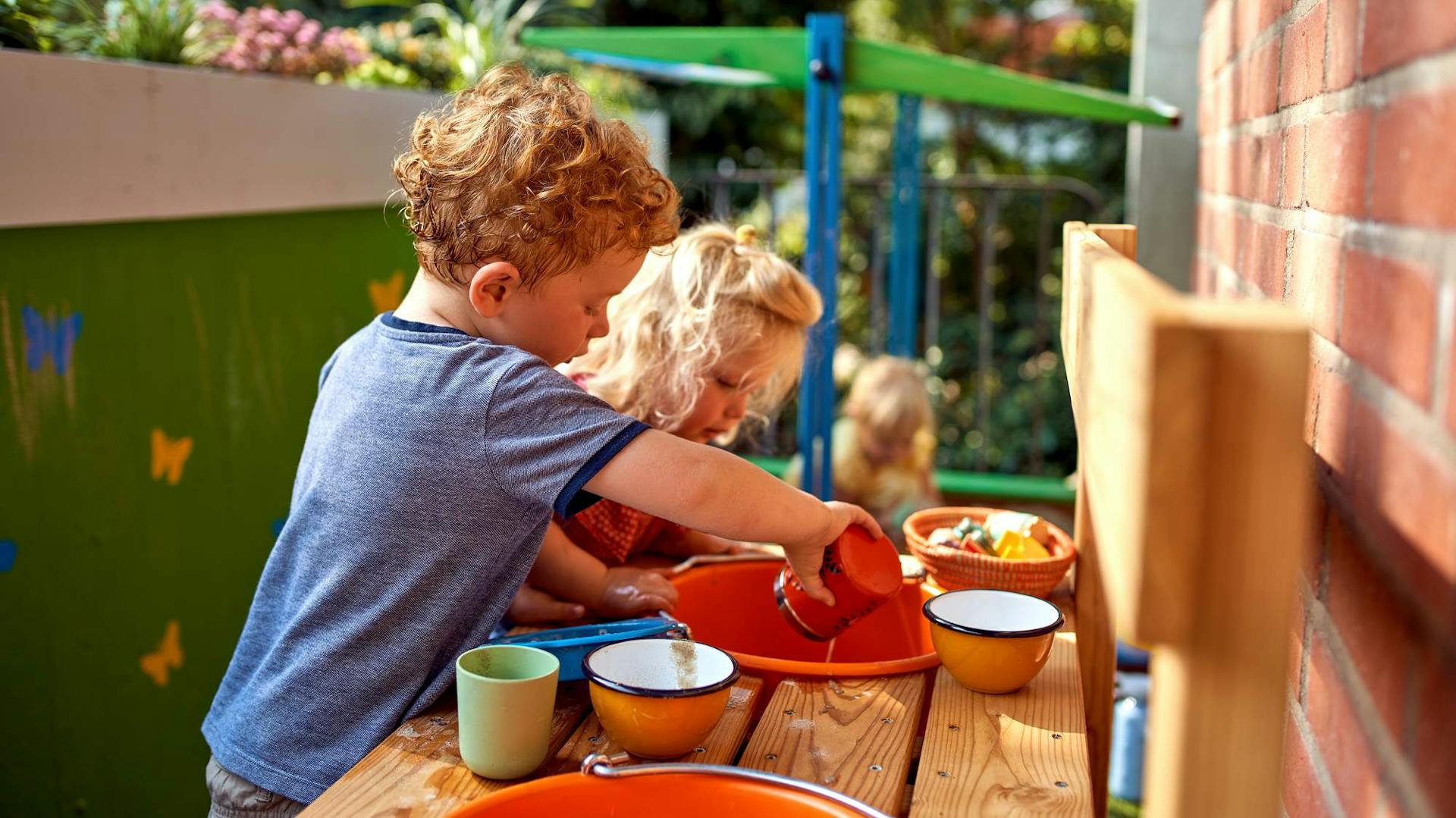 Junge und Mädchen spielen an Matschküche auf Balkon.