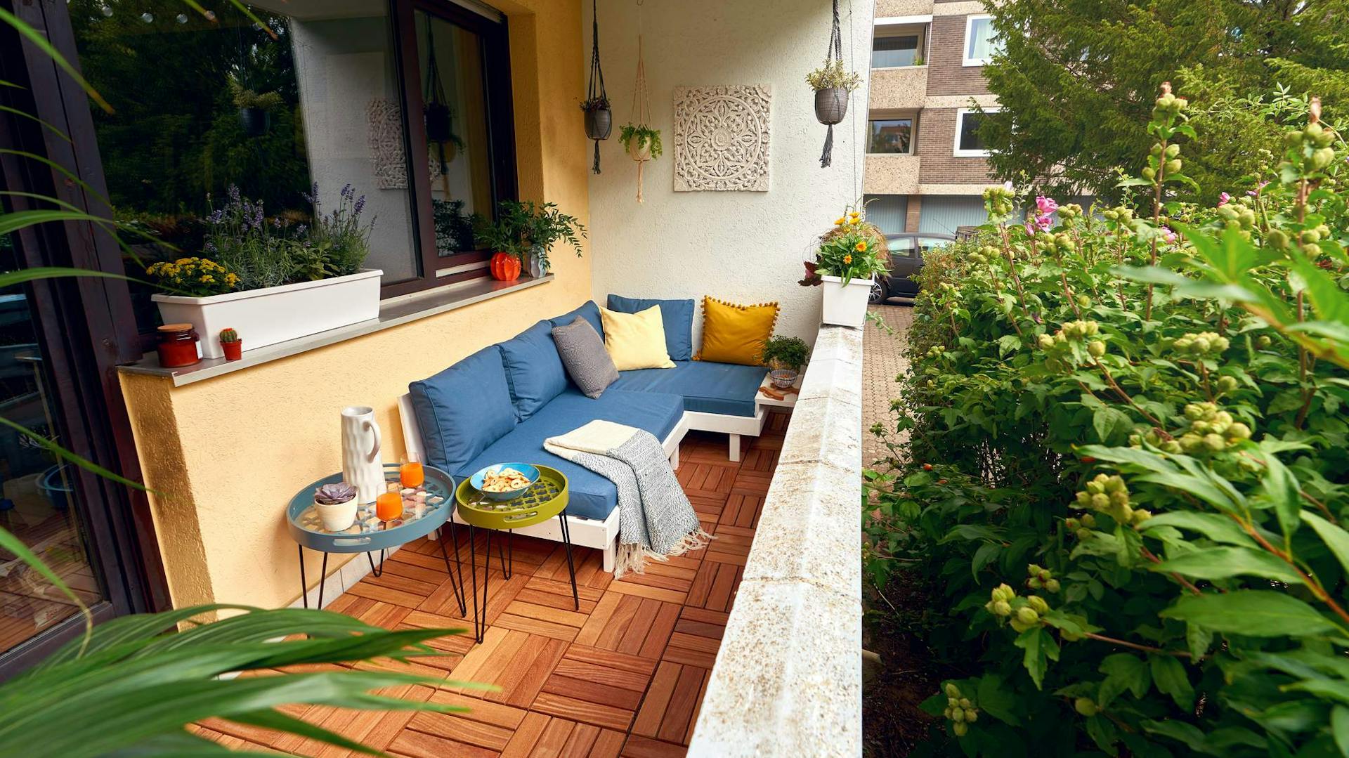 Balkon mit Holzfliesen und Loungemöbeln