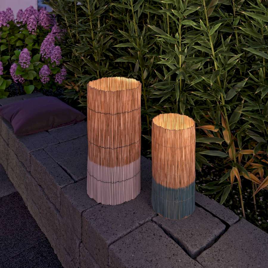Zwei Bambus Windlichter im Garten bei abendlichen Lichtverhältnissen.