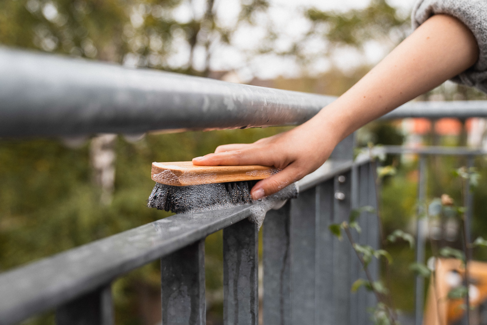 Balkongeländer mit Bürste reinigen, um Balkon winterfest zu machen