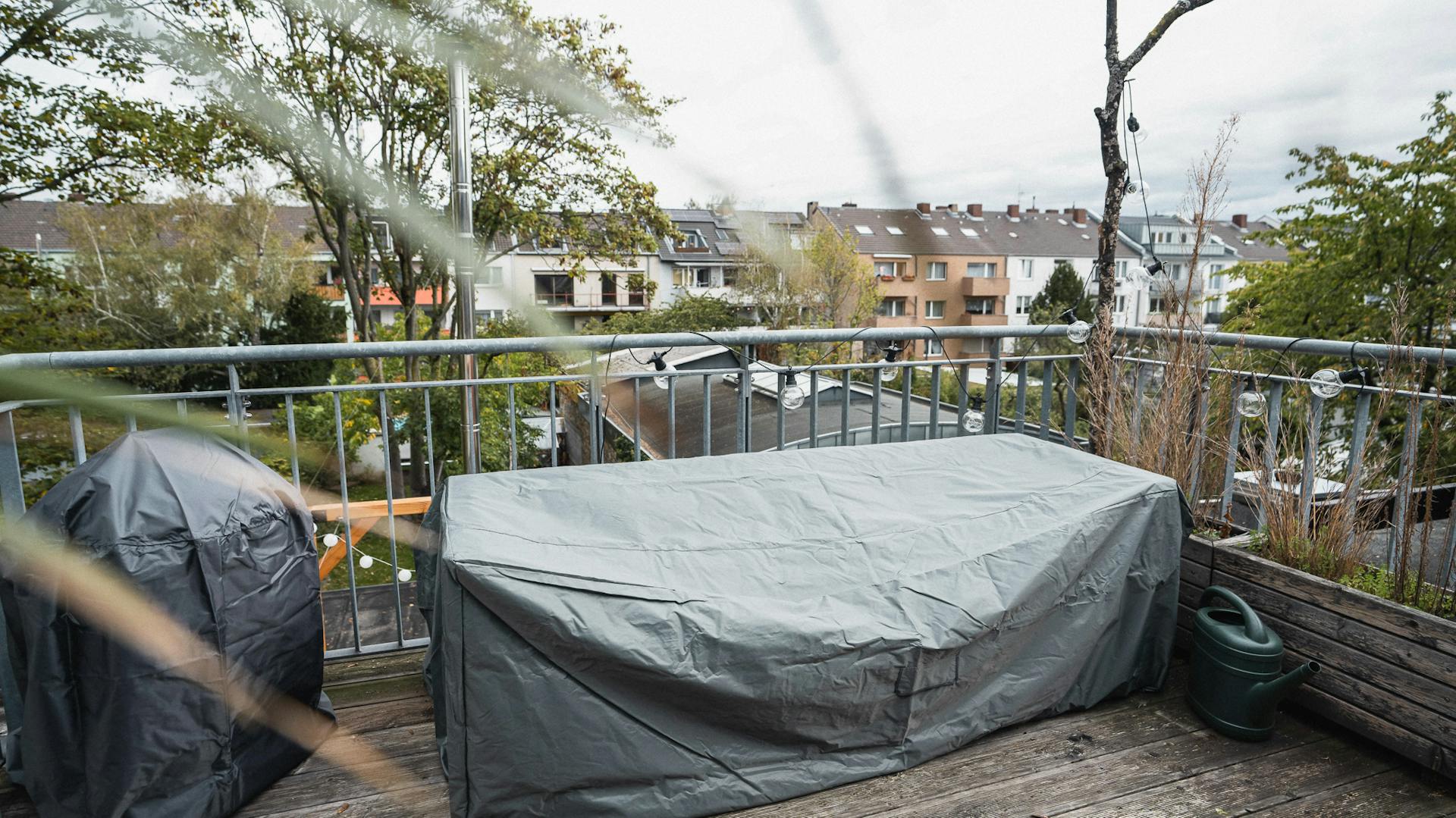 Balcone a prova di inverno con mobili e grill sotto teli di protezione