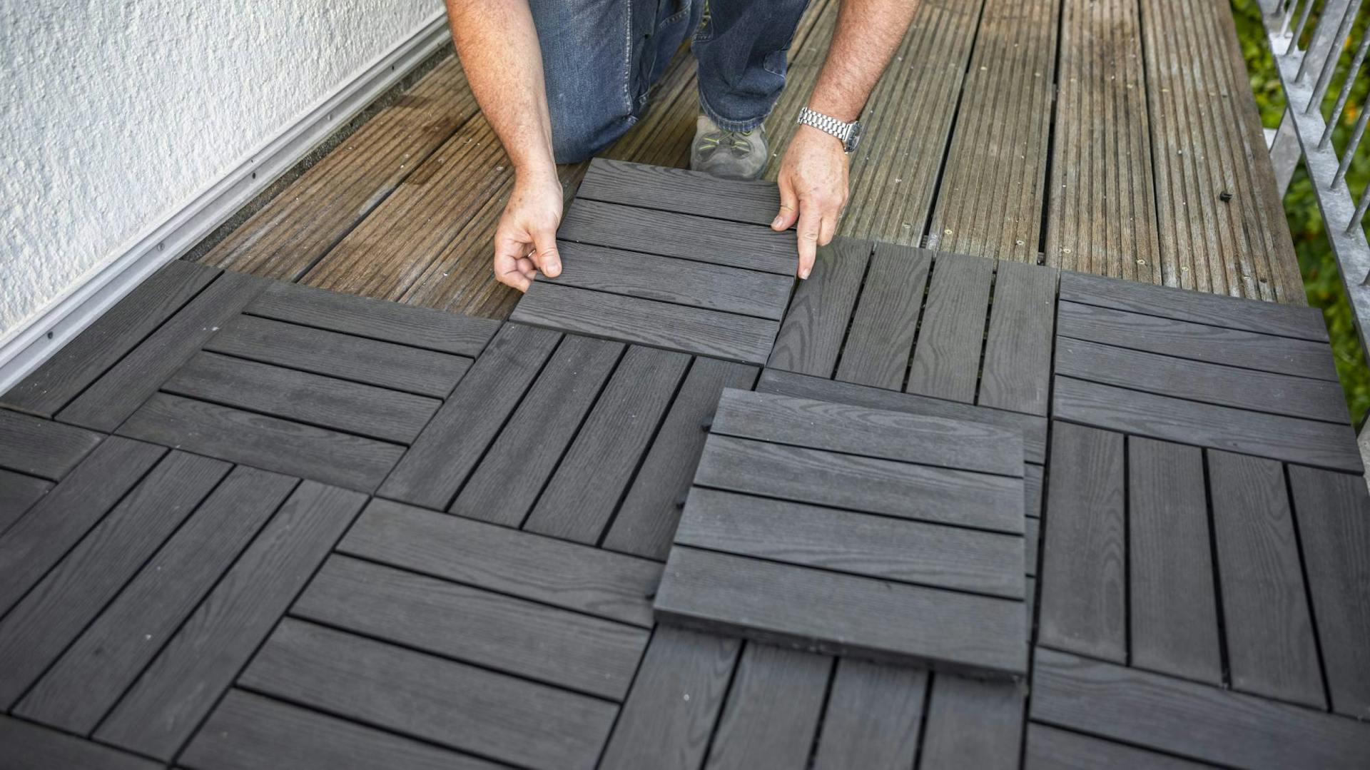 Heimwerker verlegt WPC-Klickfliesen auf dem Balkon.