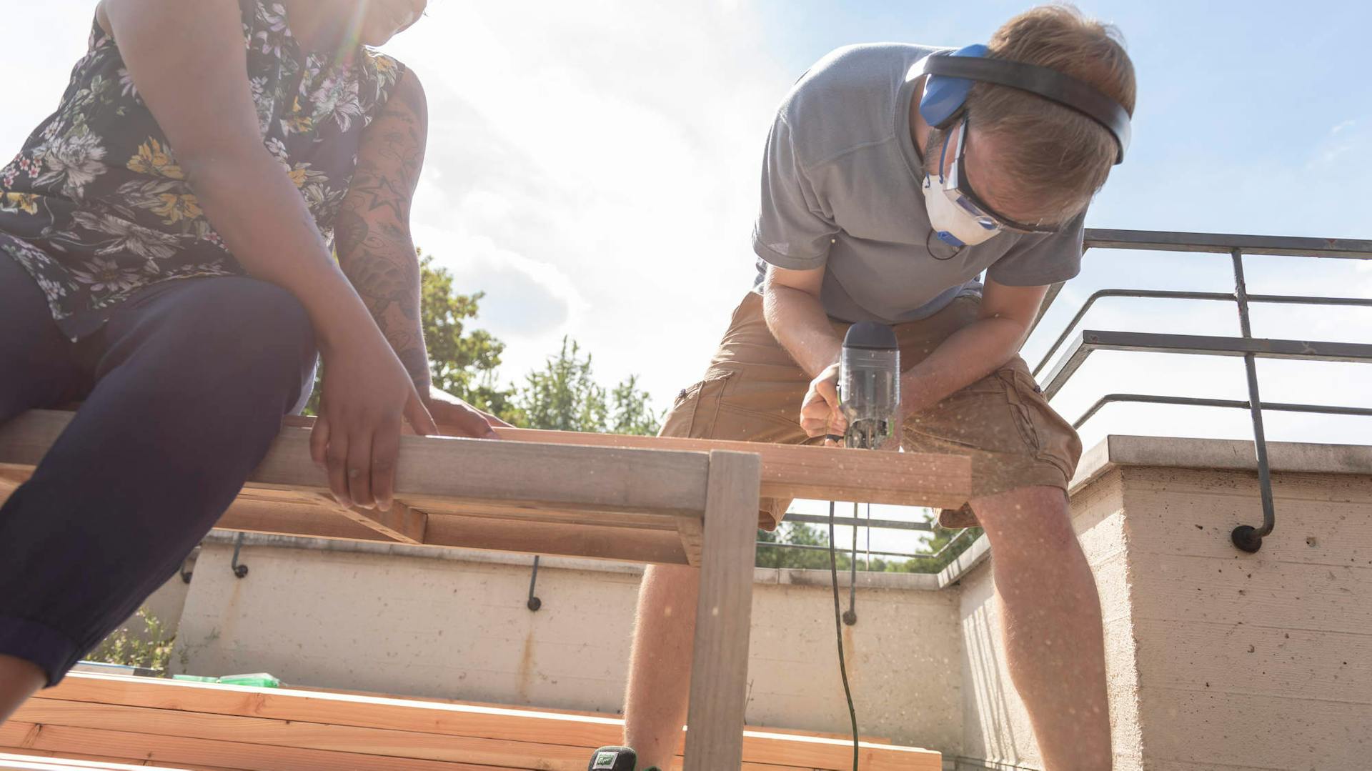 Mann sägt eine Terrassendiele zu