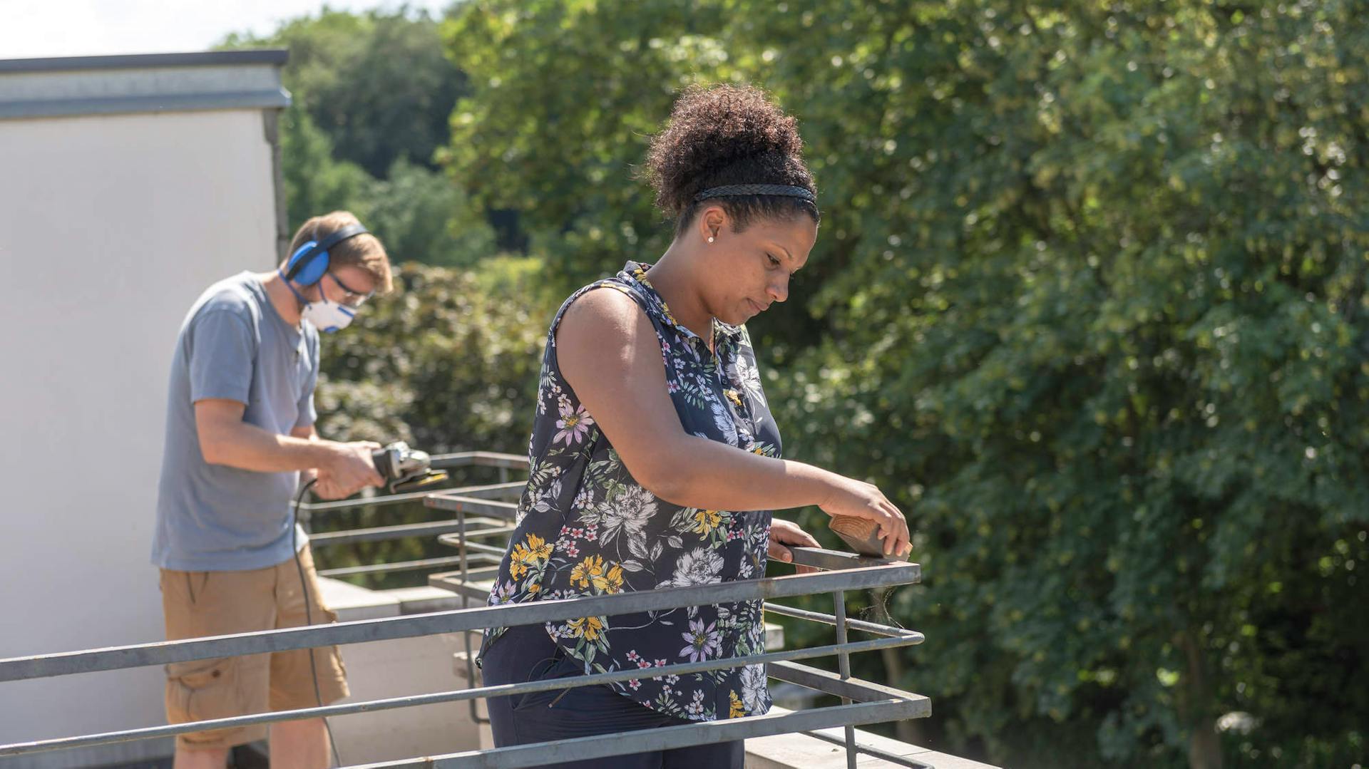 Mann und Frau schleifen Geländer ab