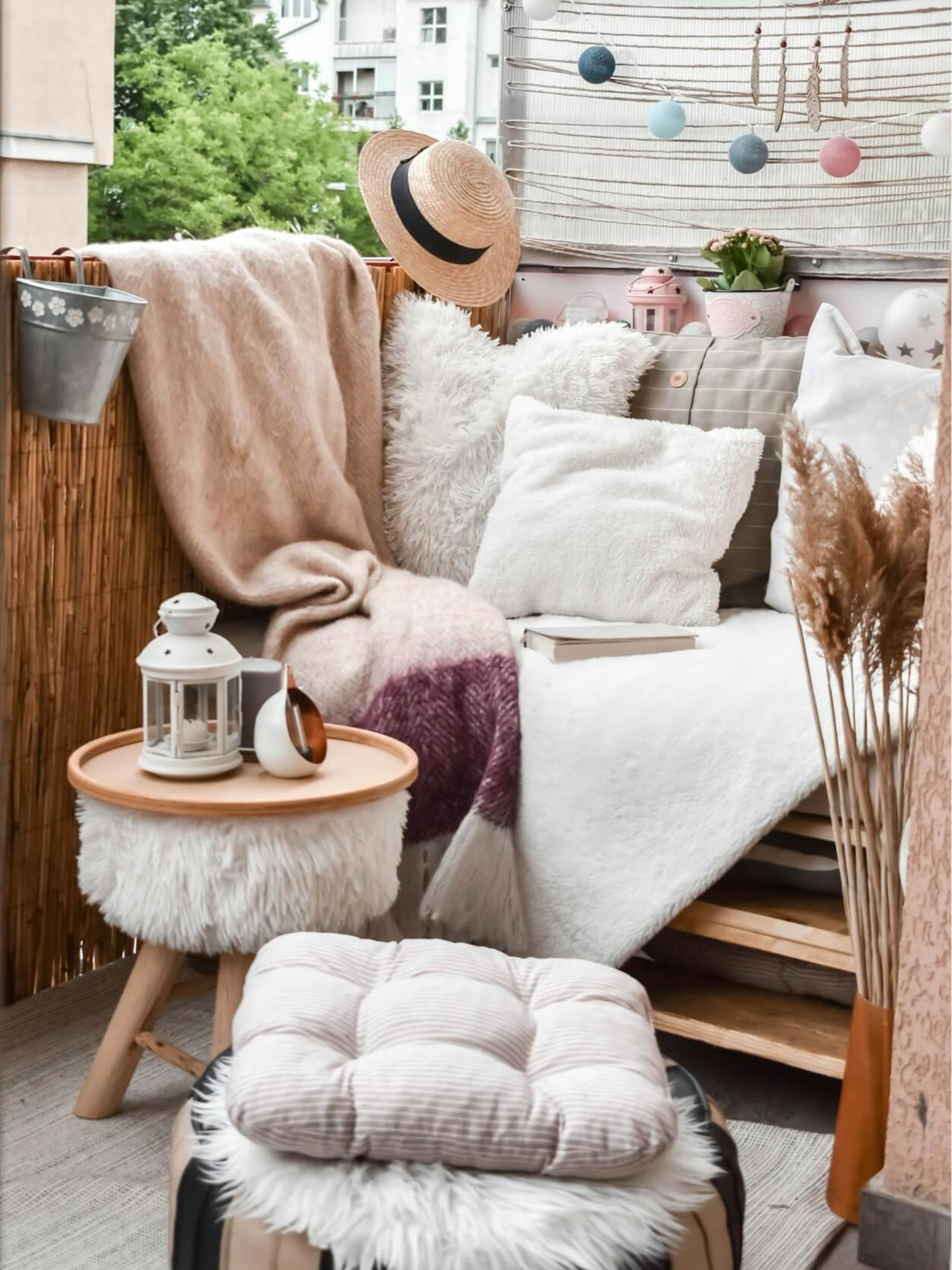 kis erkély díszpárnákkal, ülőkével, növényekkel és fényfüzérrel