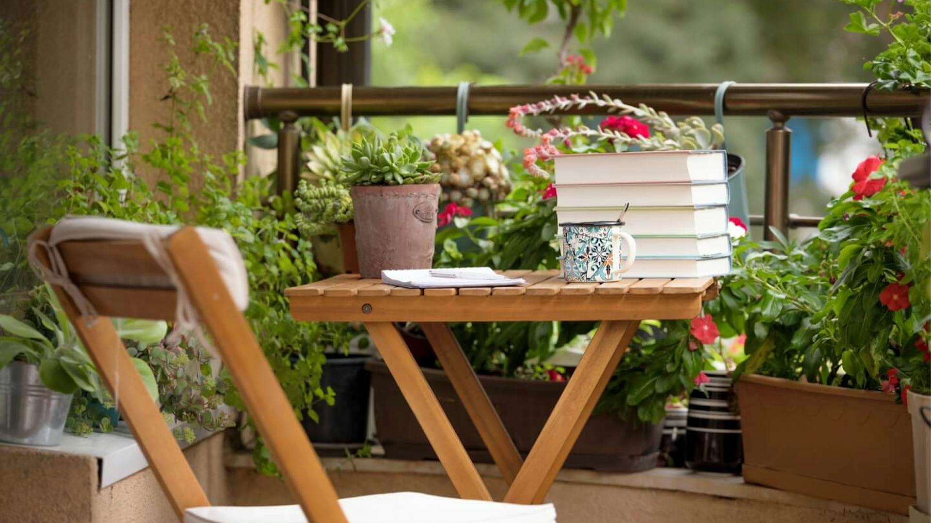 Drevený stôl a stolička na balkóne s rastlinami