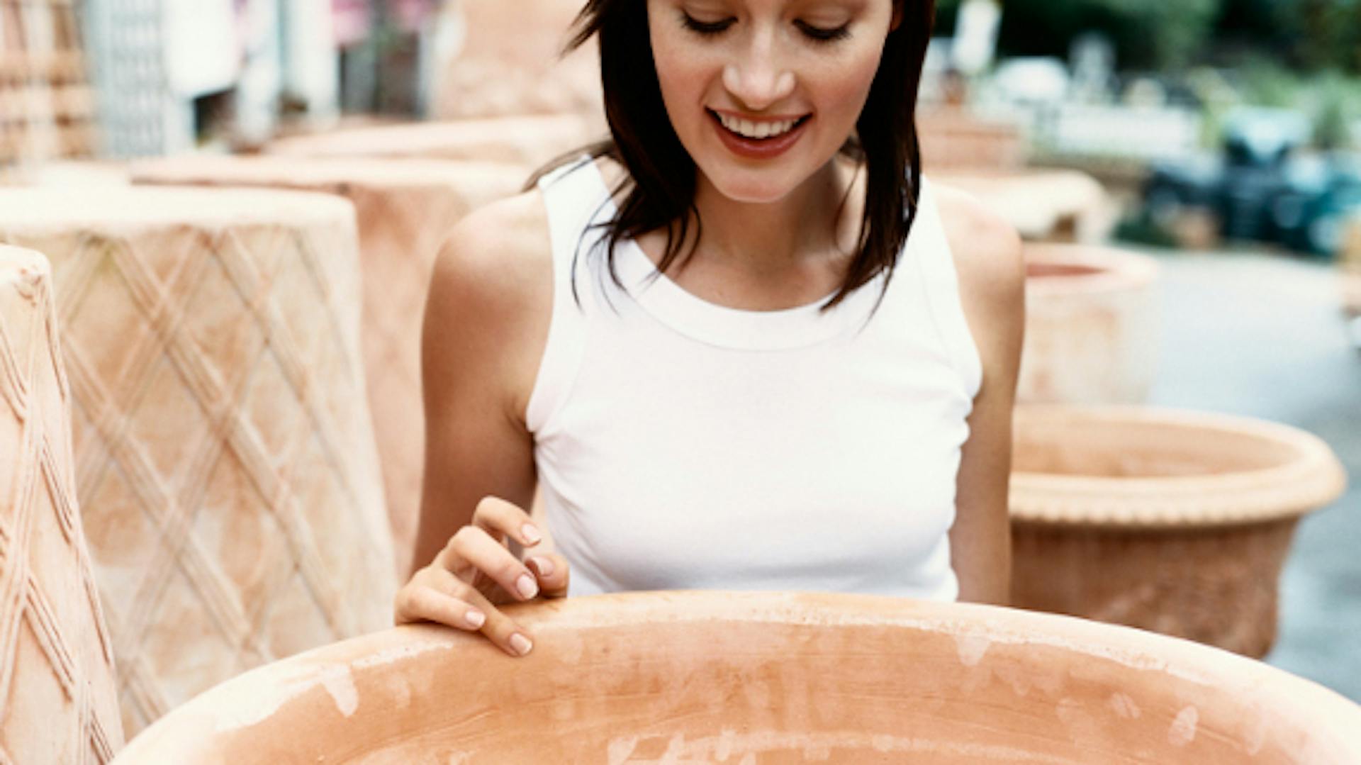 Frau guckt sich großes Outdoor-Pflanzgefäß an.