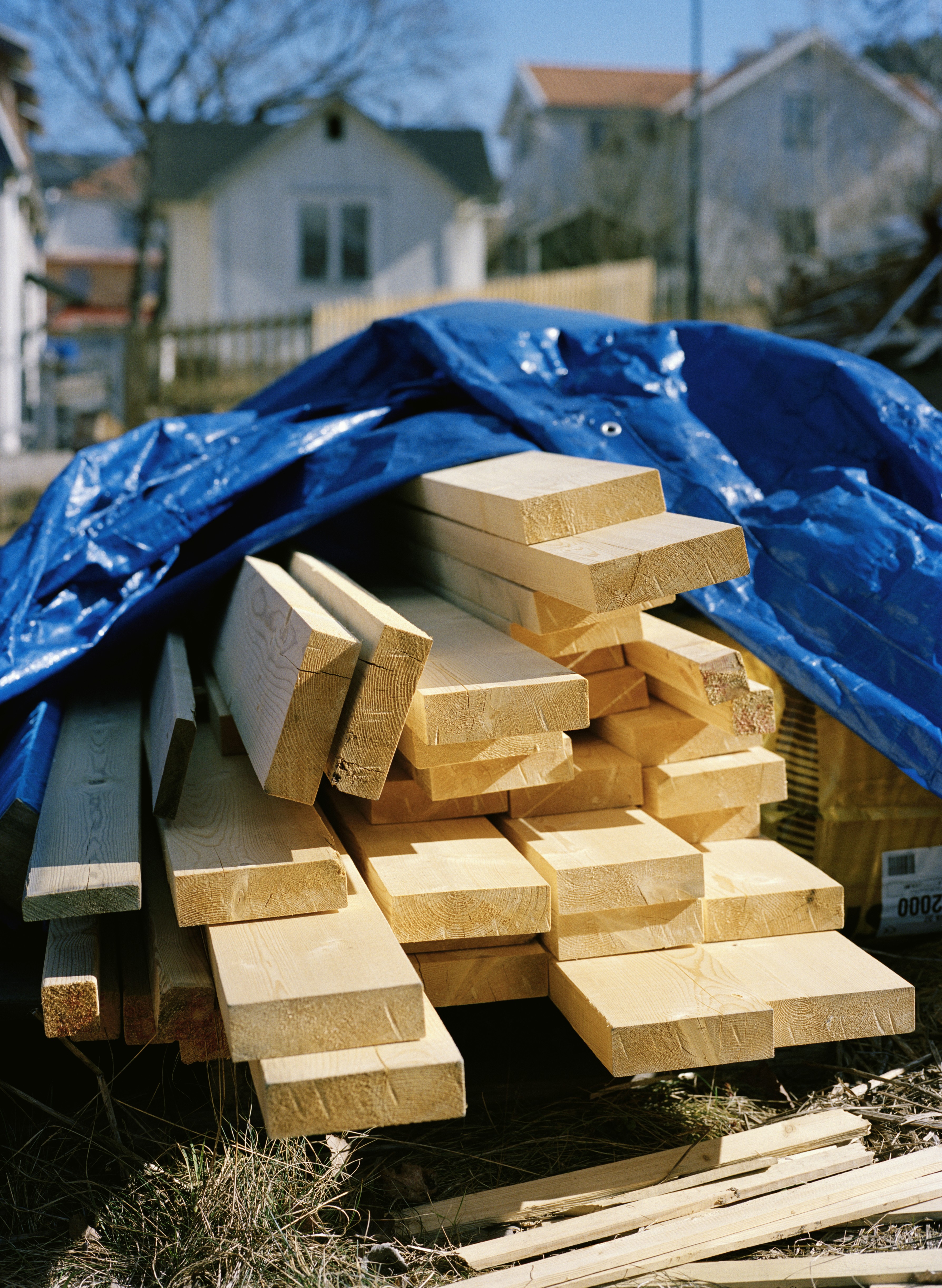 Holzbalken liegen unter einer blauen Plane.