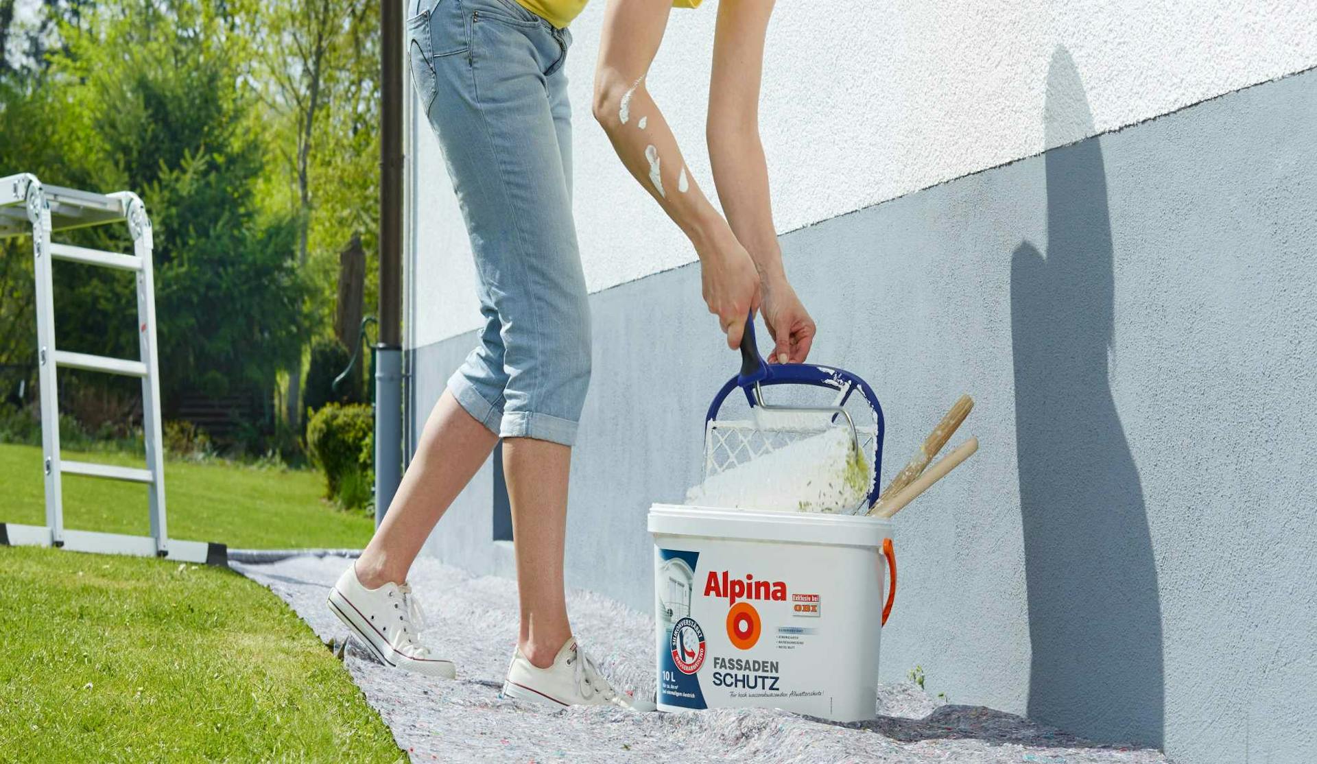 Un’amante del fai da te pittura la superficie all’esterno con una pittura per facciate.