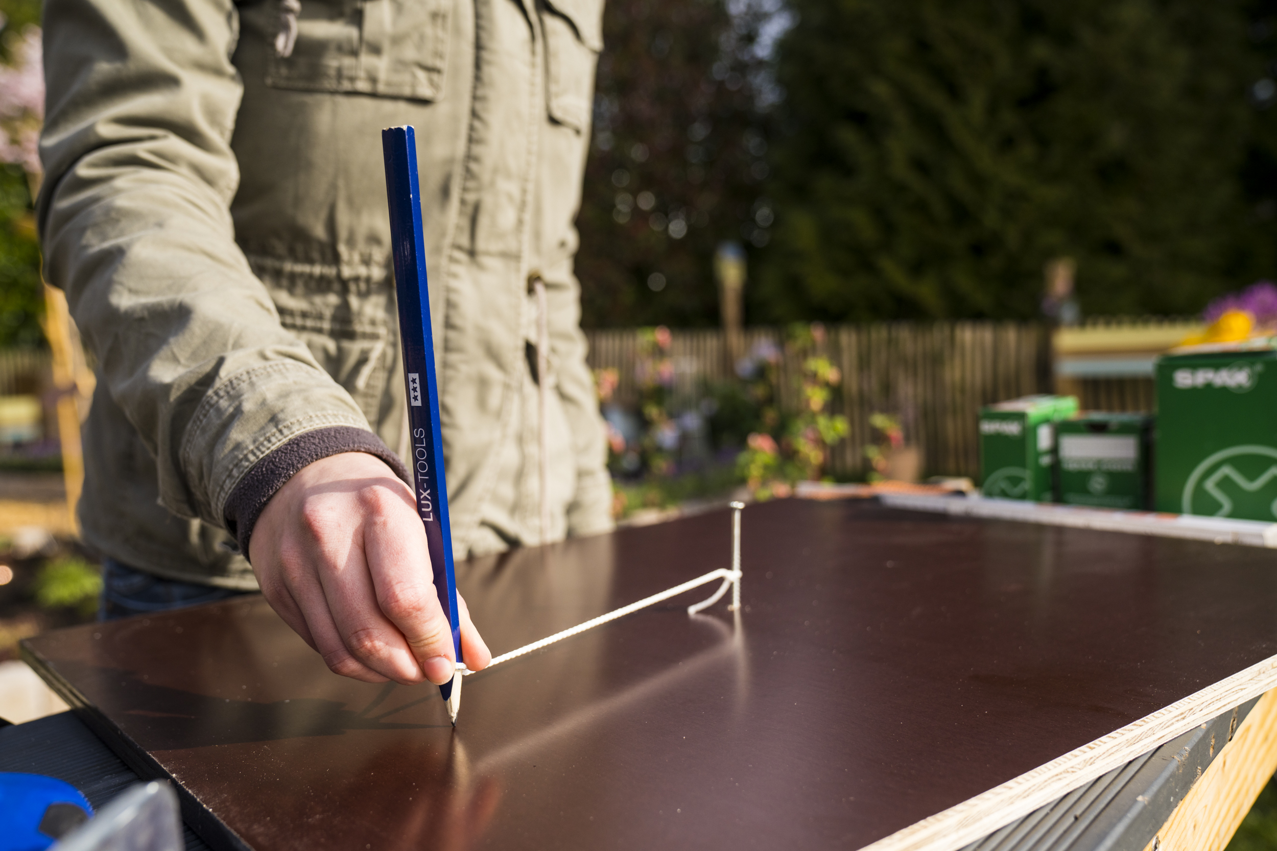 Kutil vyznačí správné rozměry dna bramborové věže na dřevěné desce tak, že tužkou obtočí šroubek s provázkem.