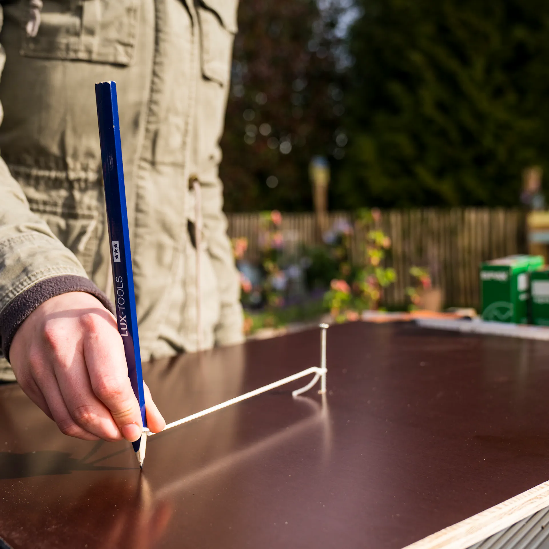 Kutil vyznačí správné rozměry dna bramborové věže na dřevěné desce tak, že tužkou obtočí šroubek s provázkem.