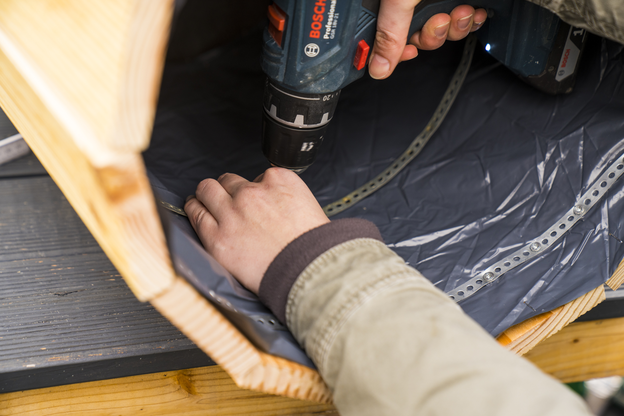 Kutil připevní děrovanou pásku ke stabilizaci bramborové věže nad dveřmi.