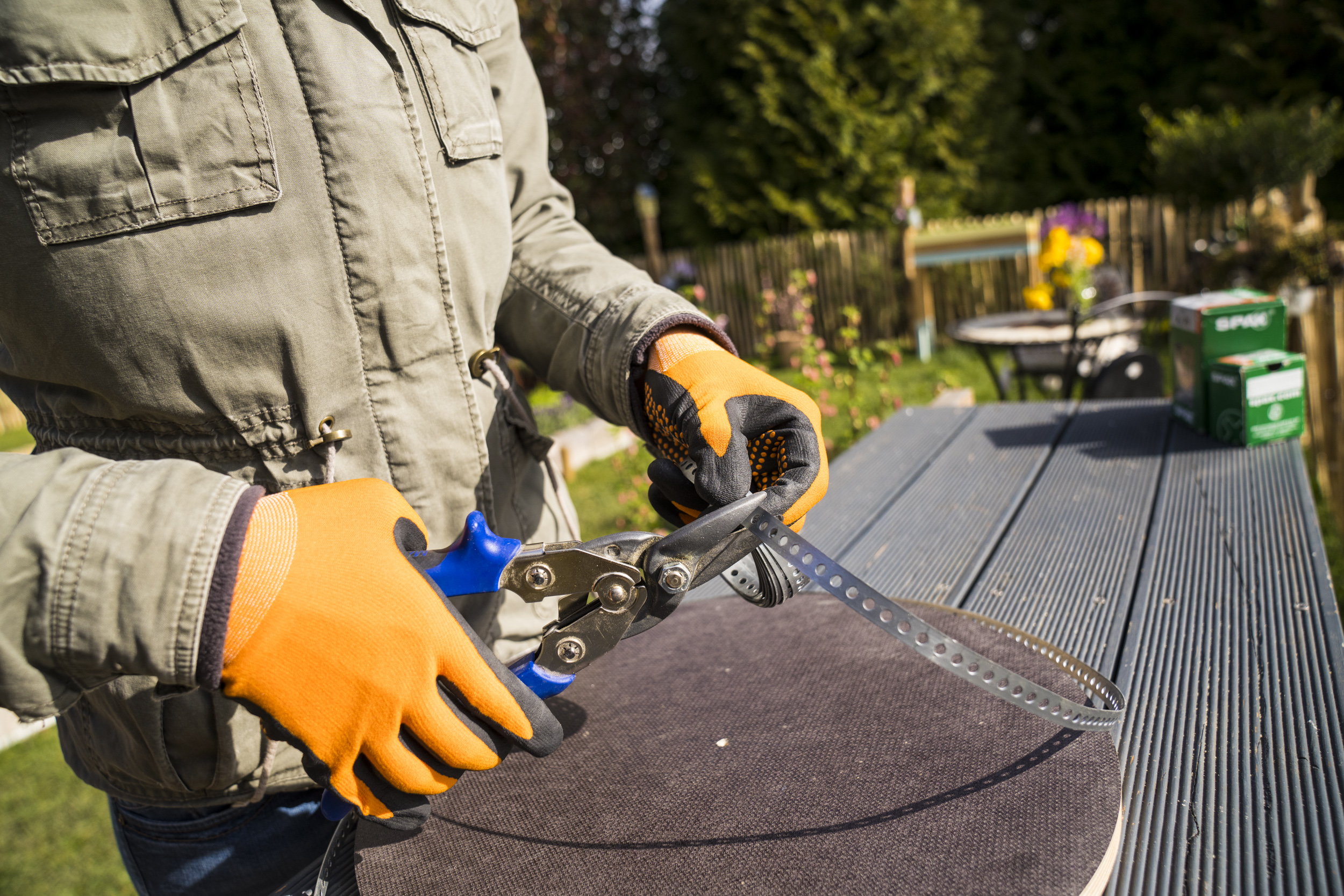 Kutil používá nůžky na kov ke stříhání perforované pásky pro stavbu věže na brambory.