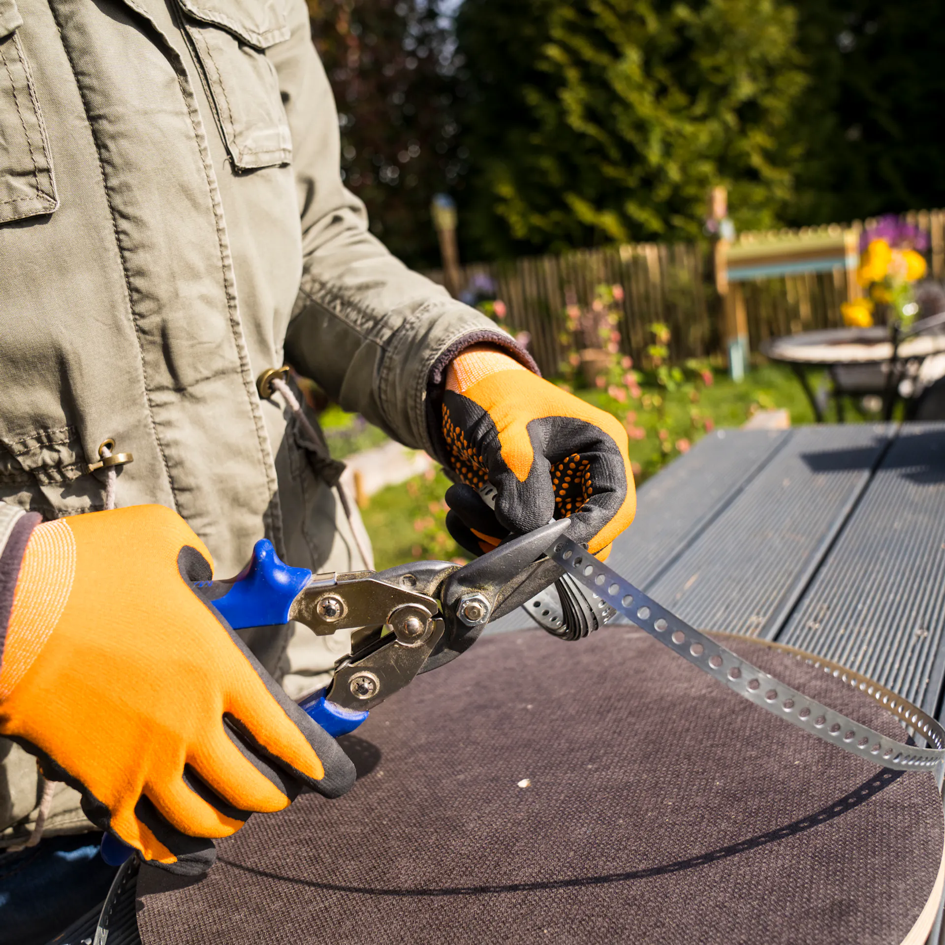 Kutil používá nůžky na kov ke stříhání perforované pásky pro stavbu věže na brambory.