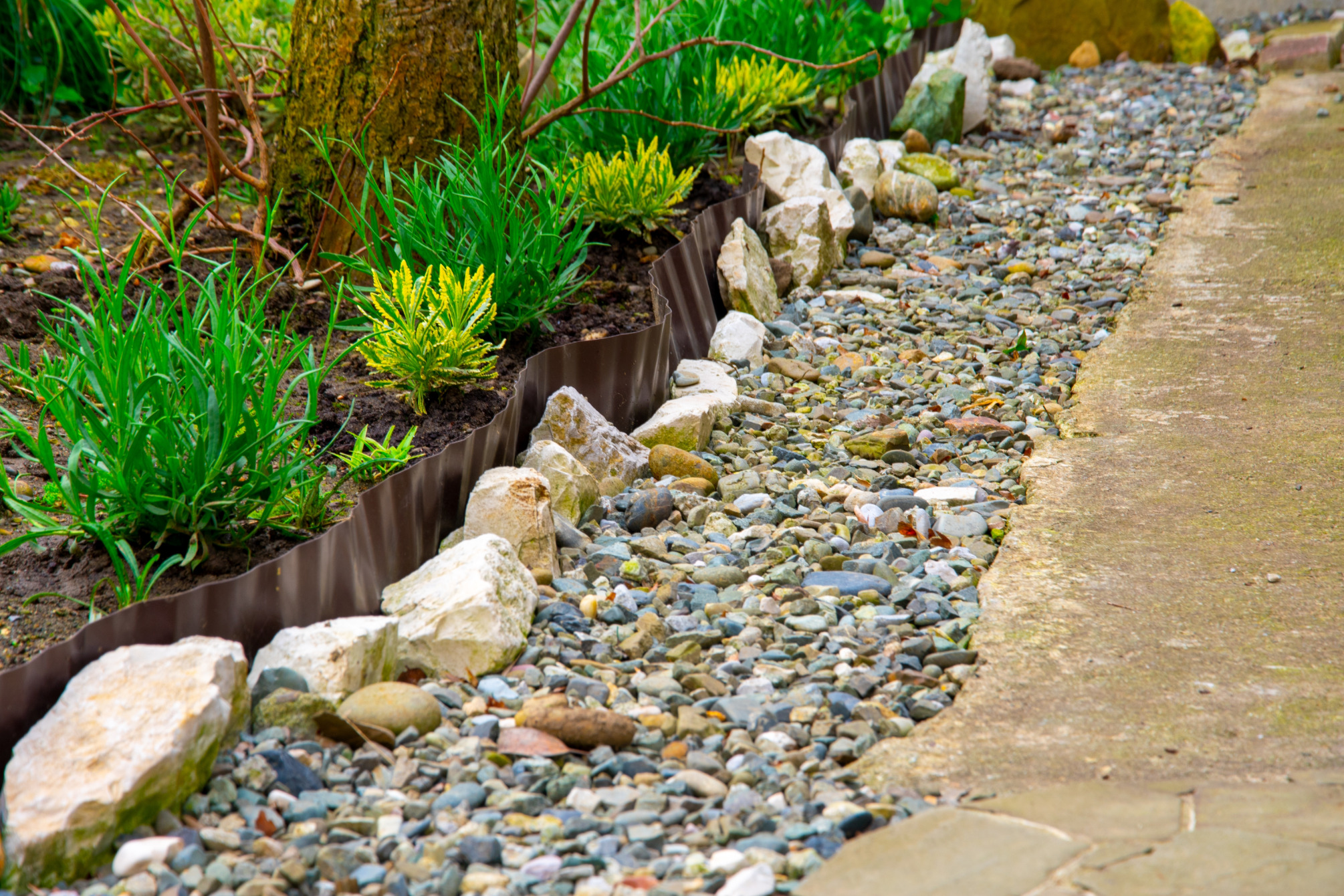Ágyás műanyagból és nagy kövekből készült szegéllyel.