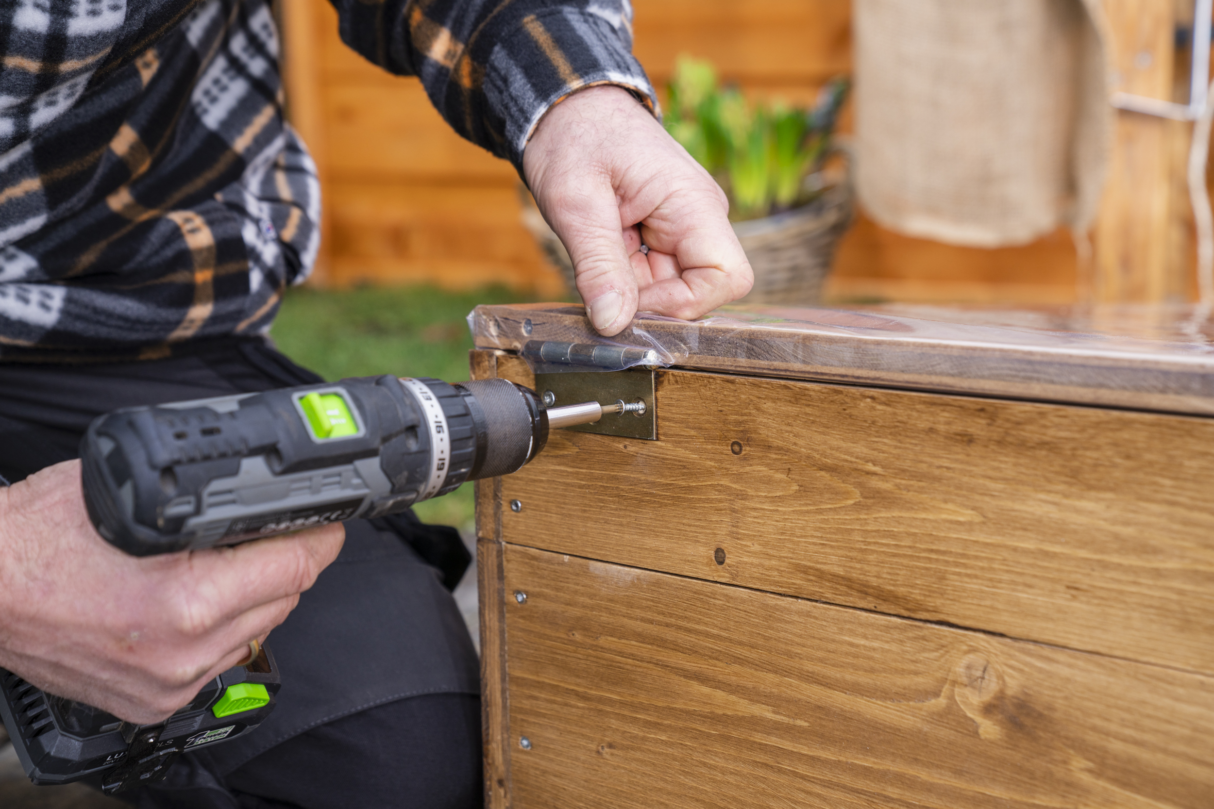 A személy felcsavarozza a melegágy fedelét