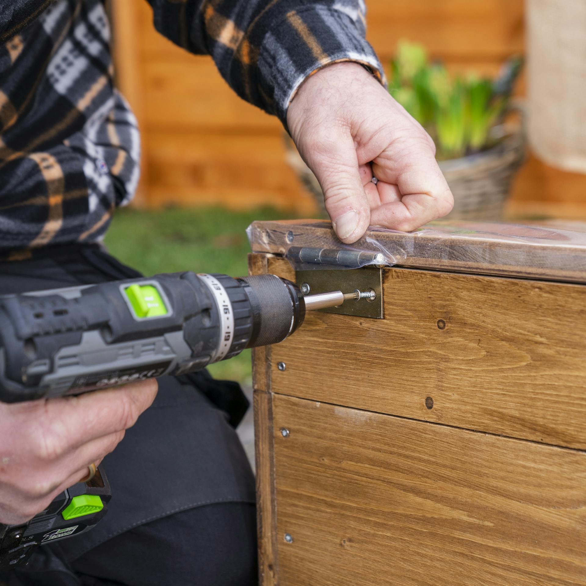 Person schraubt Deckel am Frühbeet fest