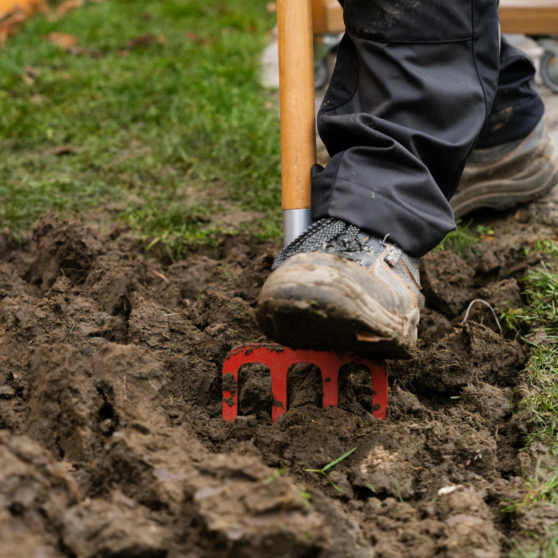 Eine Person lockert Erde mit Grabegabel.