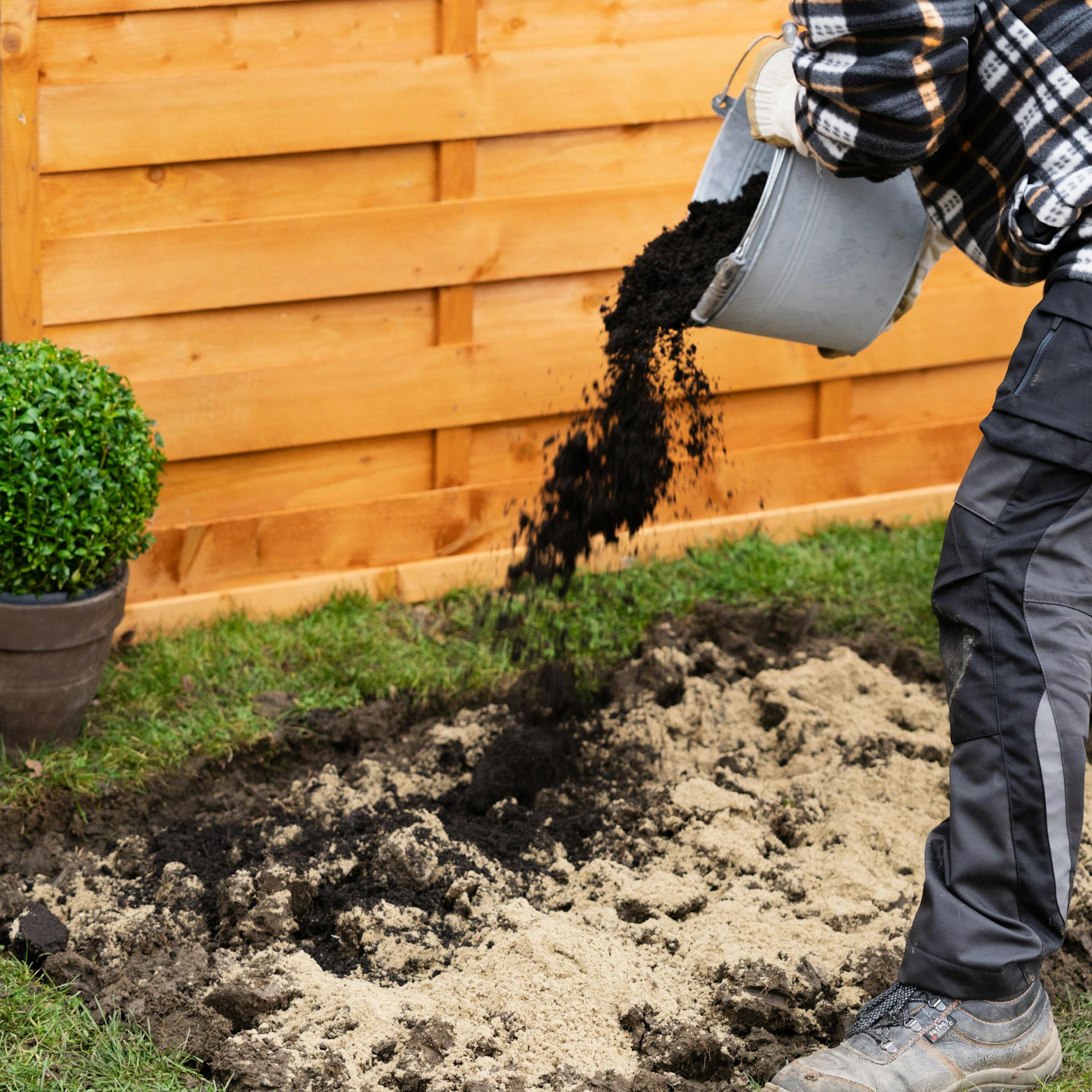 Eine Person mischt Sand und Kompost in die Erde für das Frühbeet.