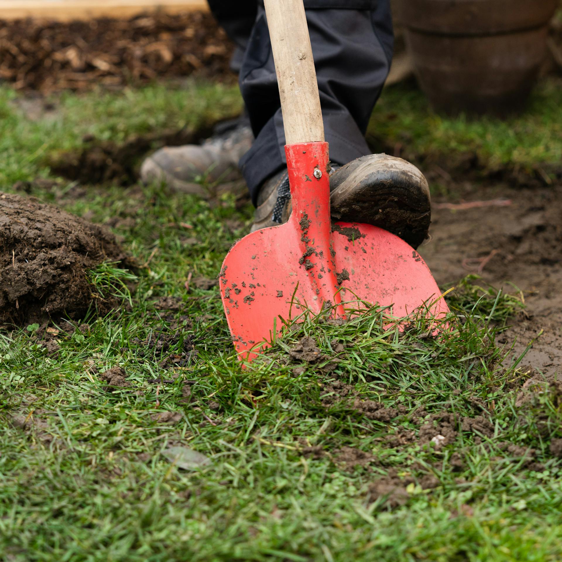 Eine Person nimmt mit einer Schaufel die Rasendecke ab.