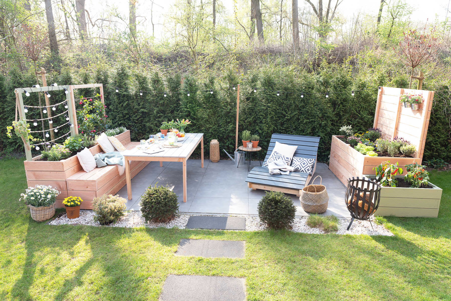 Eine Terrasse neben der sich Hochbeet Alfred einmal mit Schutzschutz und einmal mit Lichterkette befinden.