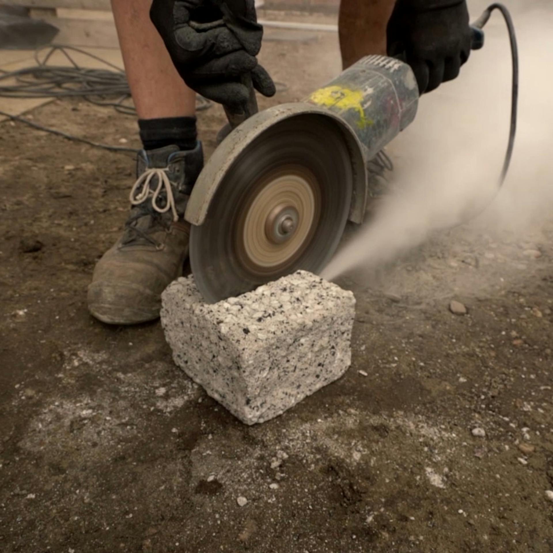 Jemand schneidet einen Stein mit einem Winkelschneider zu