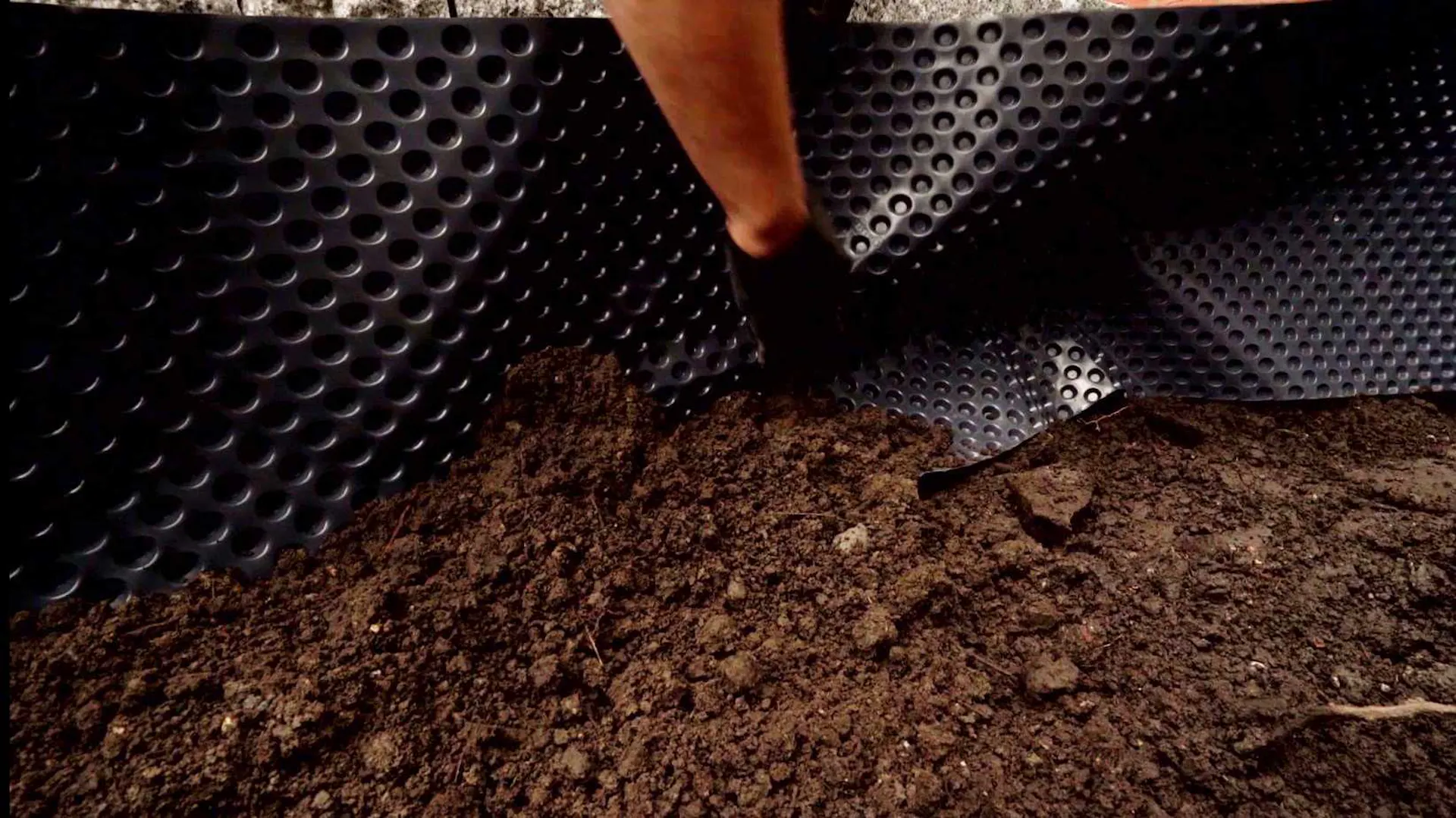 Innenansicht von Hochbeet, das am Rand mit Folie ausgekleidet und mit Erde befüllt ist.