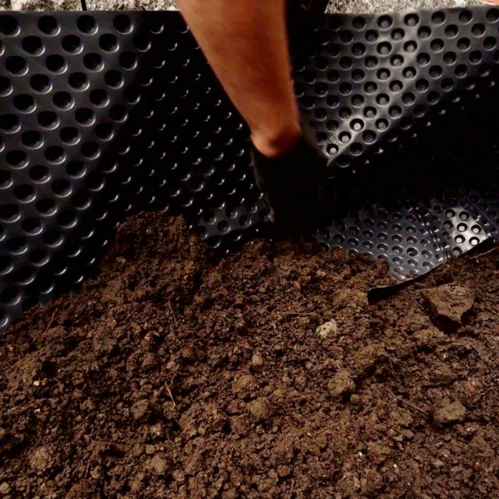 Jemand verkleidet ein Hochbeet mit Noppenfolie