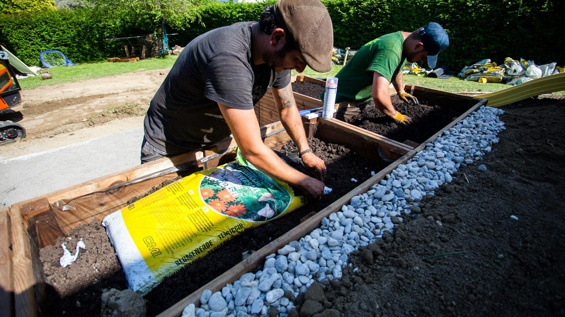 Ein Hochbeet wird von zwei Männern aufgefüllt.