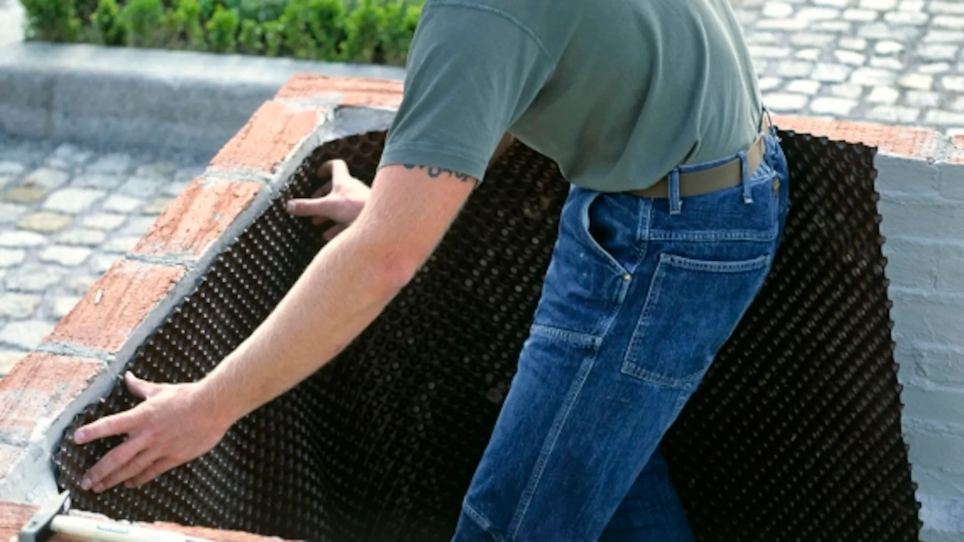 Heimwerker bringt Folie an Innenseite des Holz-Hochbeetes an.