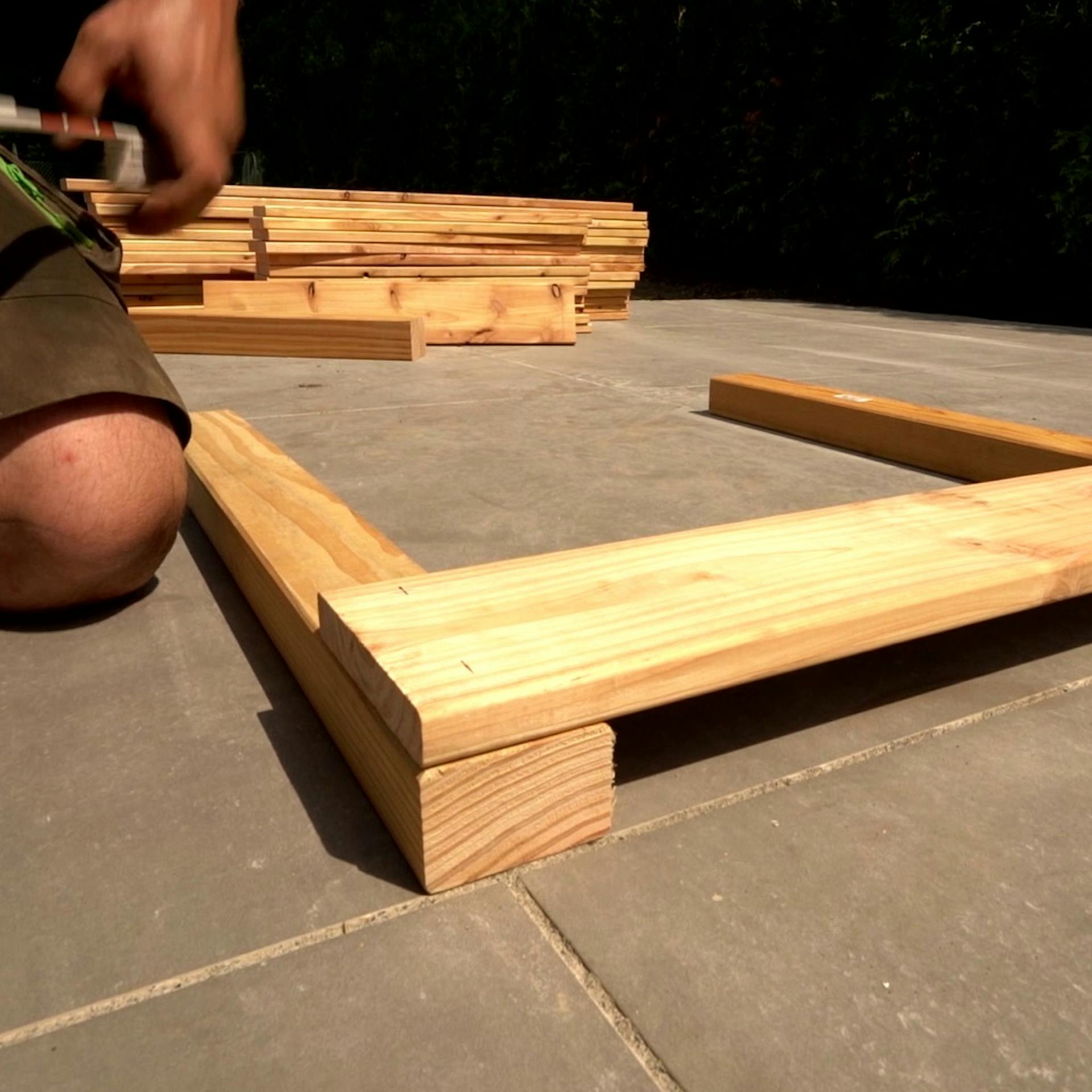 Heimwerker zeichnet Kopfteil an Bretter an