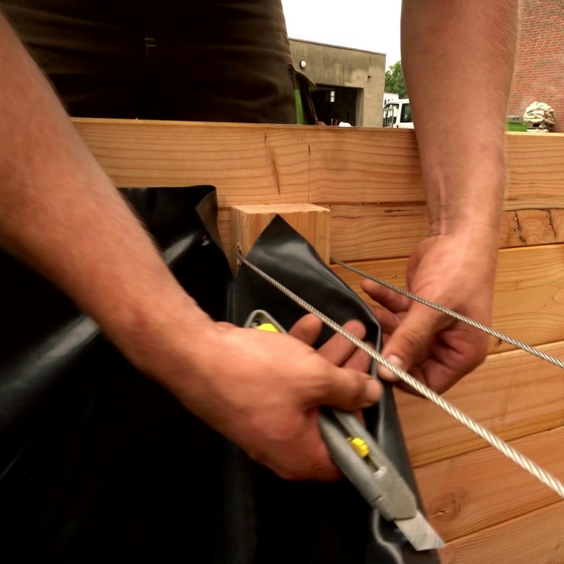 Folie im Inneren des Hochbeetes aus Holz befestigen.