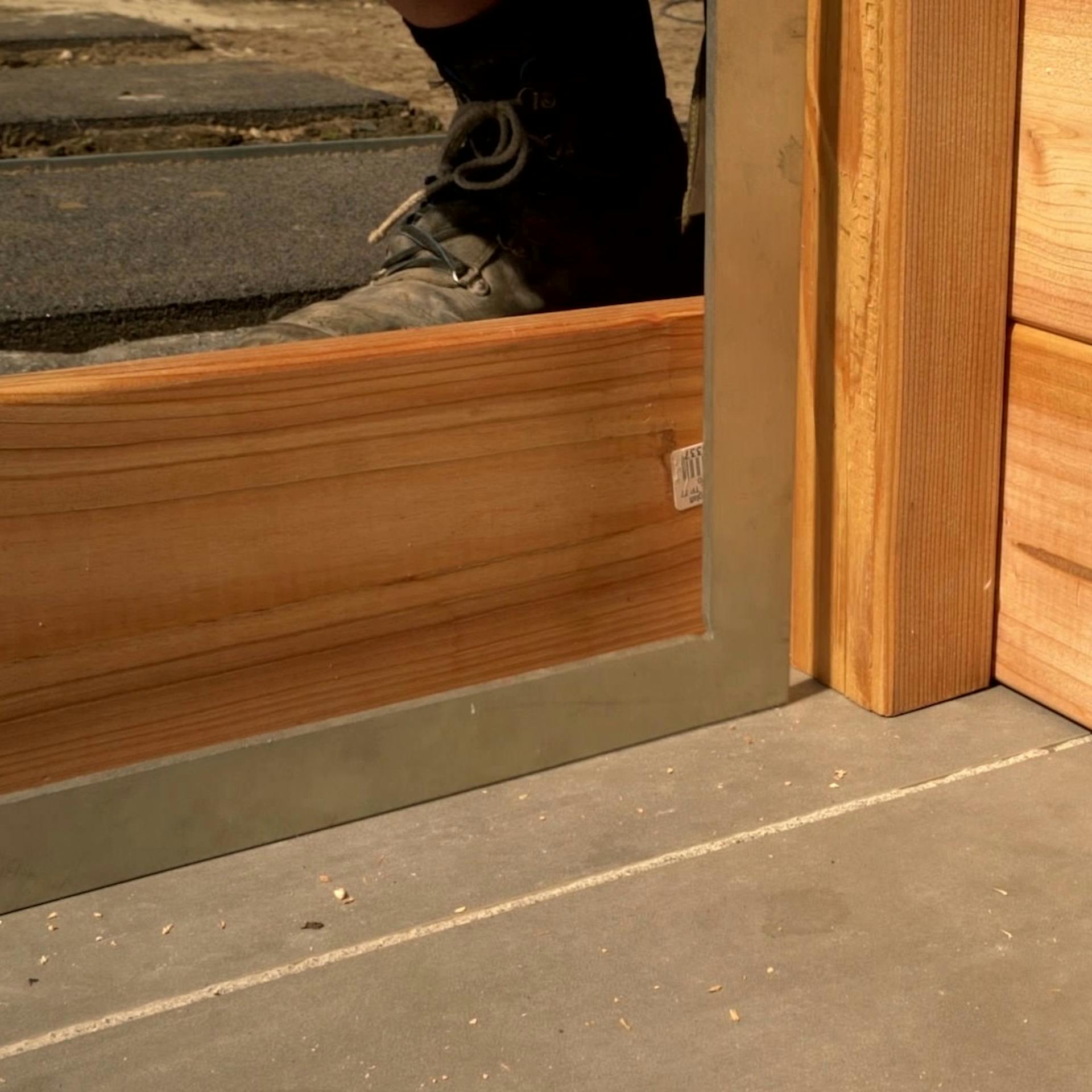 Holzbretter werden an lange Seite des Hochbeetes montiert.